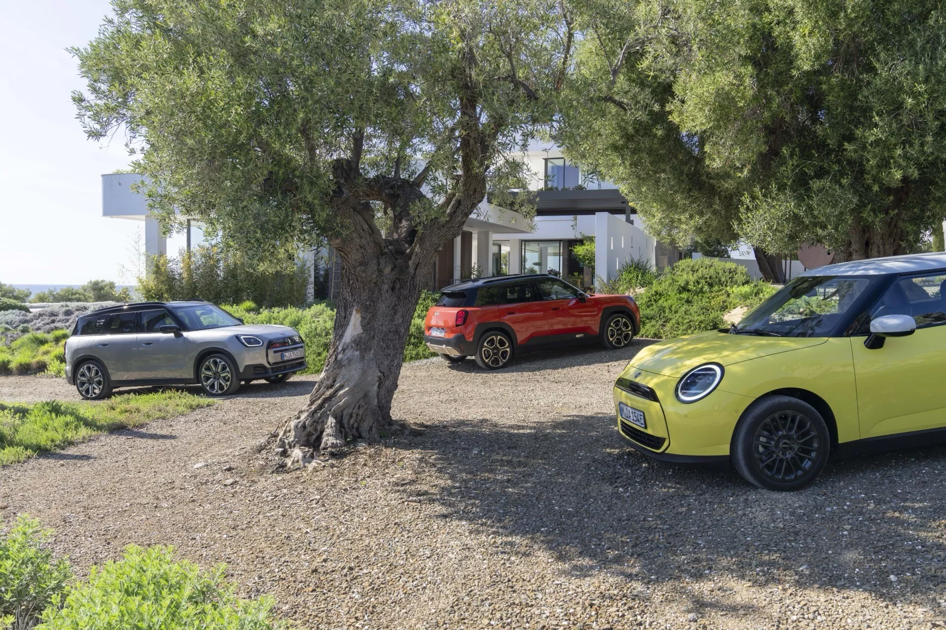 2024 Mini Aceman (J05) in vivid yellow, showcased in a scenic outdoor setting with a focus on its distinctive design, including round headlights, modern alloy wheels, and chrome grille detail