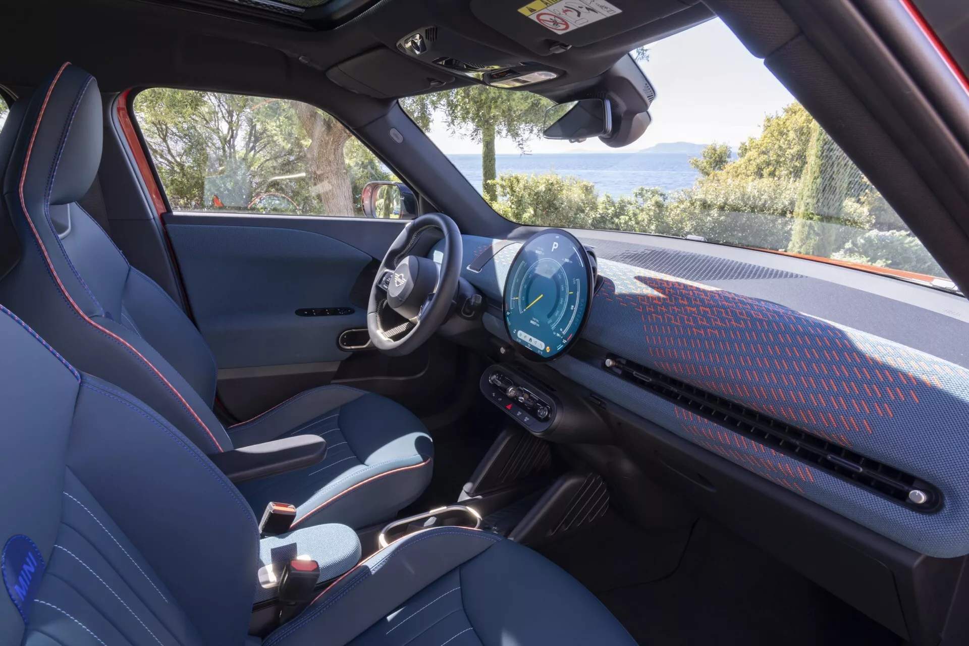 Interior view of the Mini Aceman 2024 (JO5) showcasing the modern dashboard with a digital instrument cluster and large touchscreen infotainment system, sporty seats, and minimalistic design elements
