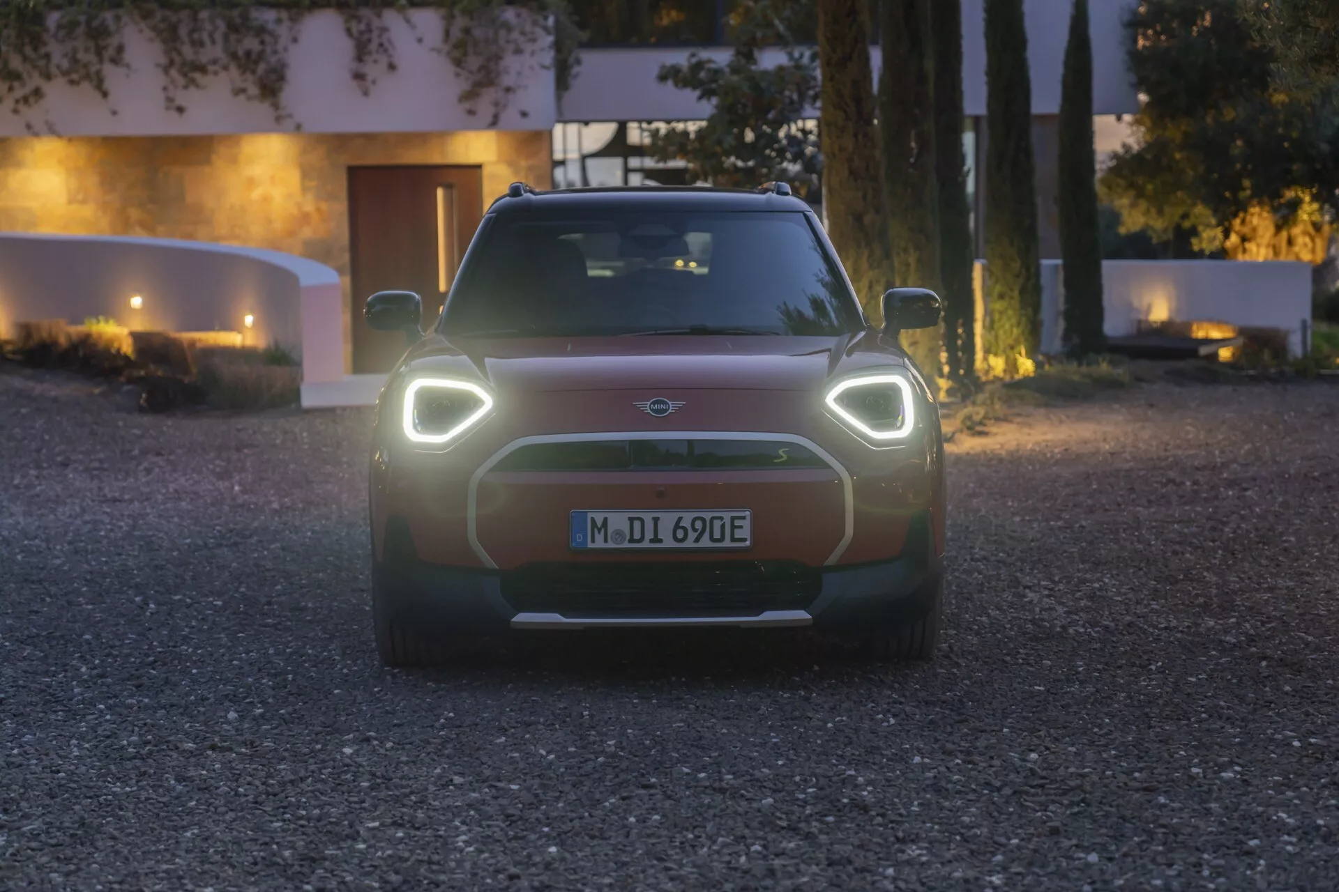 Frontal view of Mini Aceman 2024 at twilight showcasing LED headlights, stylized electric grille, and driver assistance technologies
