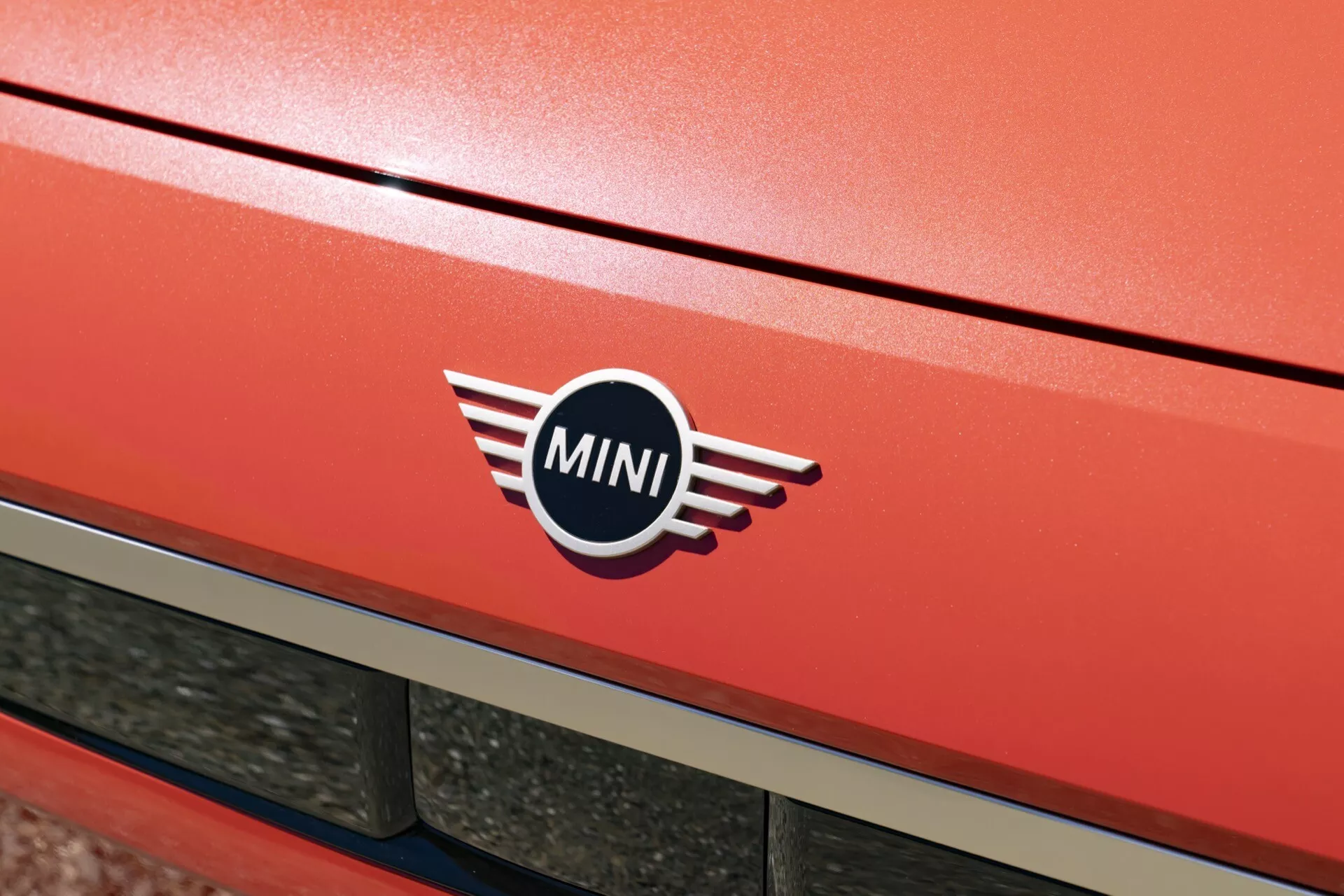 Close-up of the 2024 MINI Aceman (J05) showing the vivid red metallic rear hatch with the iconic MINI logo, hinting at the vehicle's elegance and speed