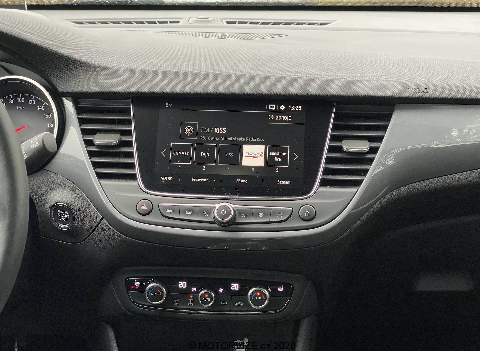 Interior dashboard view of the 2021 Opel Crossland, showcasing a centrally located touchscreen infotainment system displaying radio station information, with control knobs and buttons for audio and climate settings, stylish air vents, and part of the instrument cluster, highlighting modern vehicle technology and interior design.