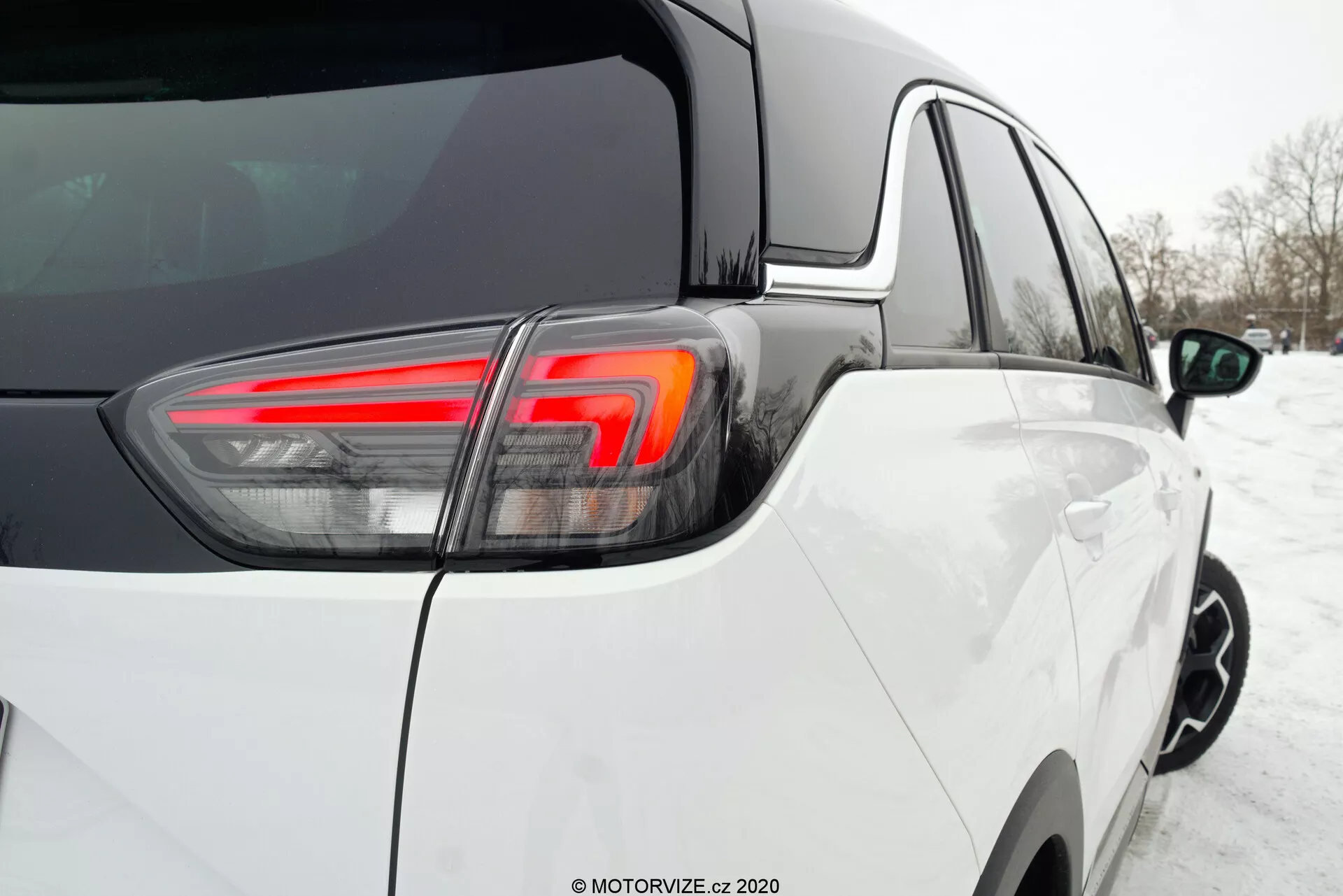 Close-up rear three-quarter angle of a 2021 Opel Crossland, highlighting the modern design with white paint finish, distinct LED tail light assembly, clean condition in a snowy environment, showcasing top-quality assembly with tight, consistent panel gaps and glossy paint.