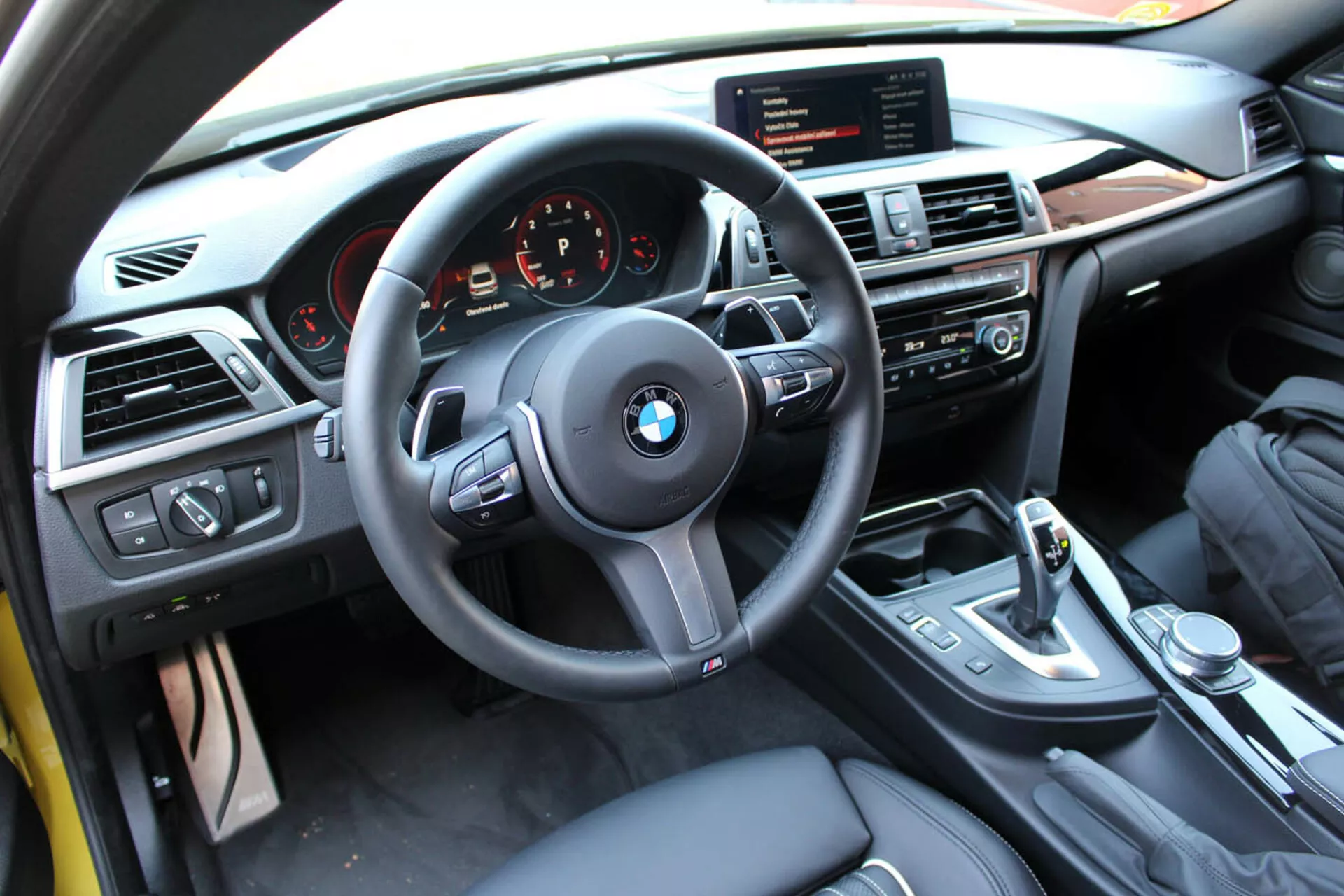 Interior view of a 2013 BMW 4 Series Coupe from driver's perspective showing steering wheel, dashboard, center console with multimedia and climate controls, gear shift lever, and luxury finishes