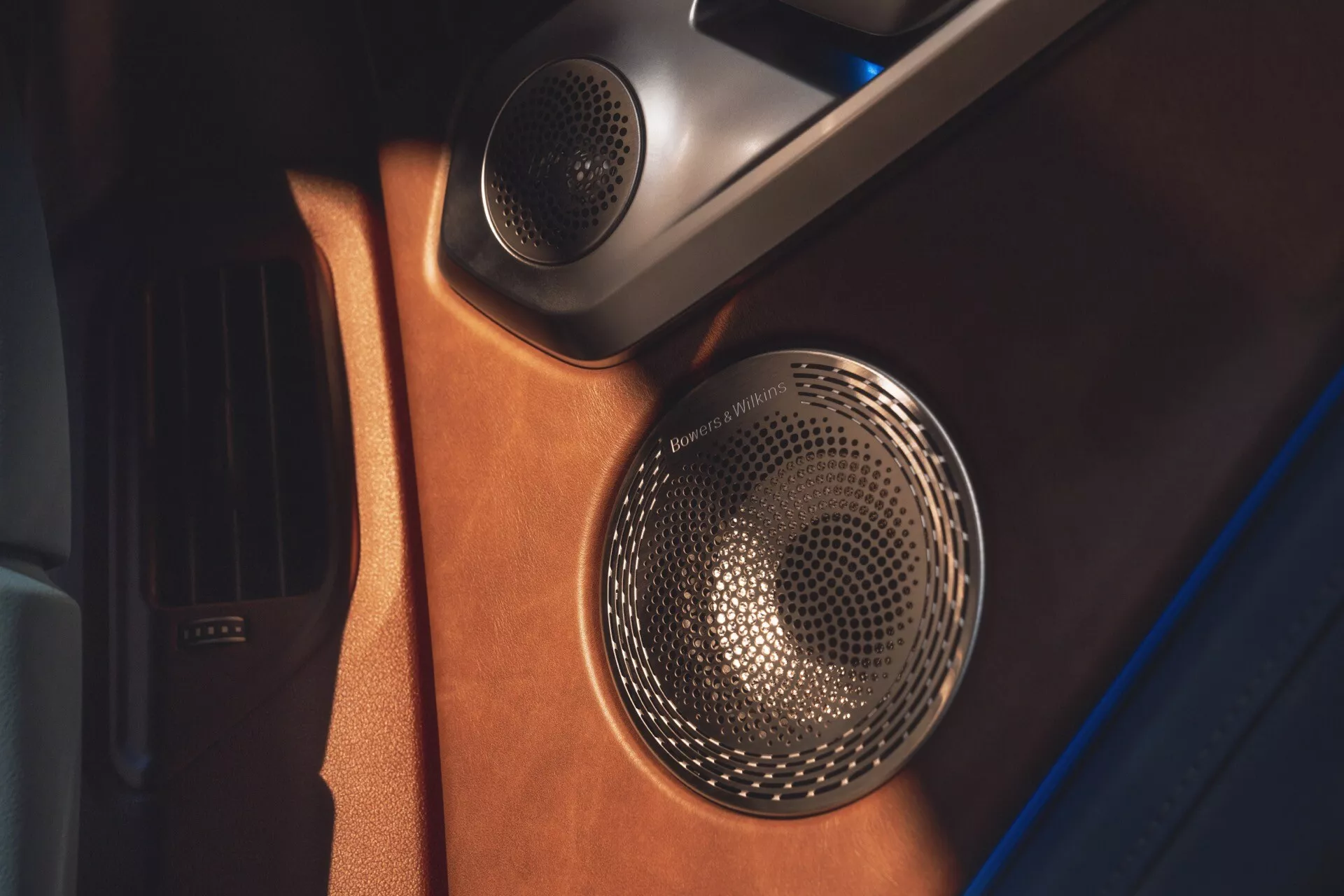 Close-up view of the BMW XM 2023 (G09) door panel highlighting the luxury sound system with a metallic speaker grill and leather finish