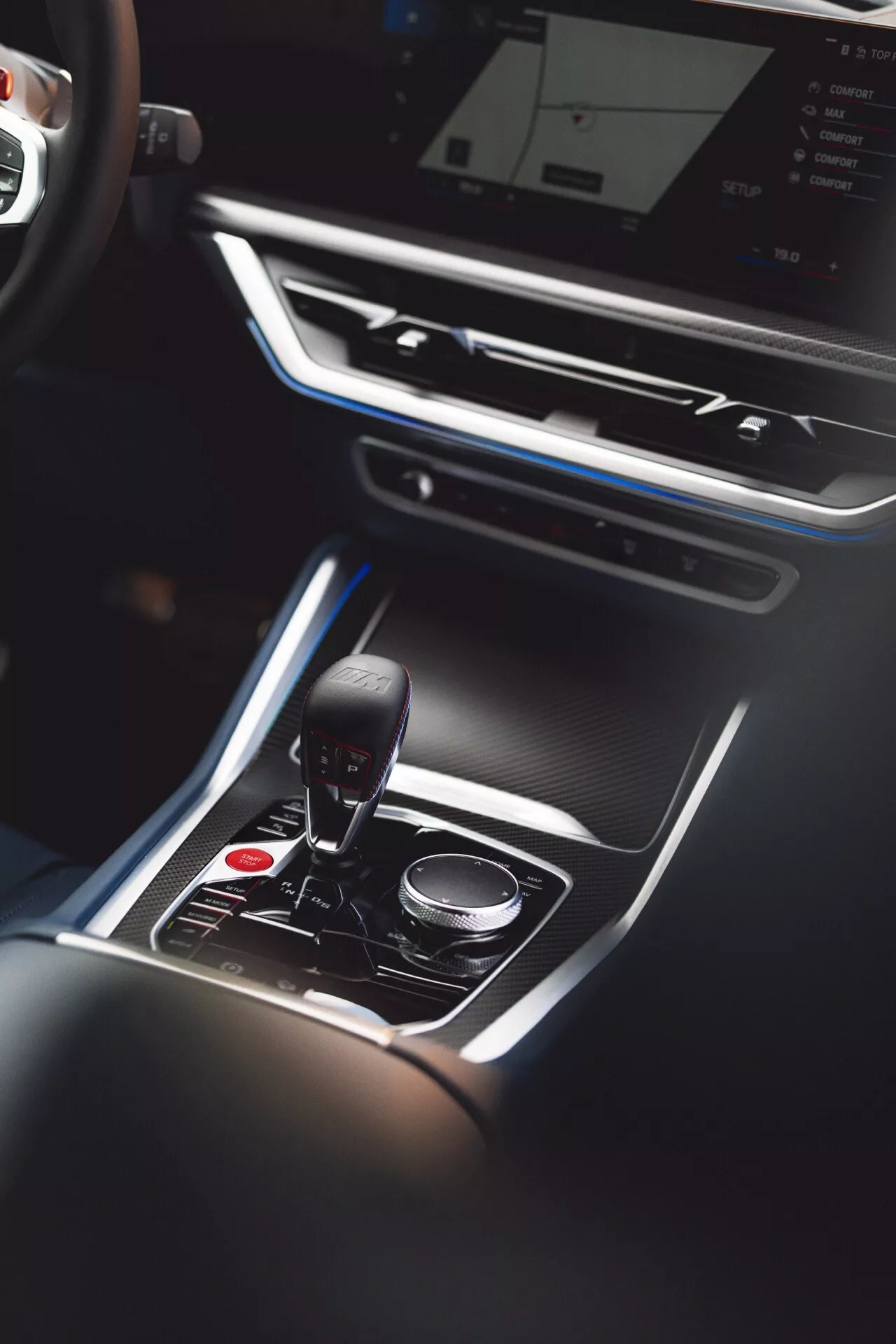 Overhead view of the BMW XM 2023 (G09) interior focusing on the central console with automatic gear shift in park position, surrounded by luxury accents and touch-sensitive multimedia control dial
