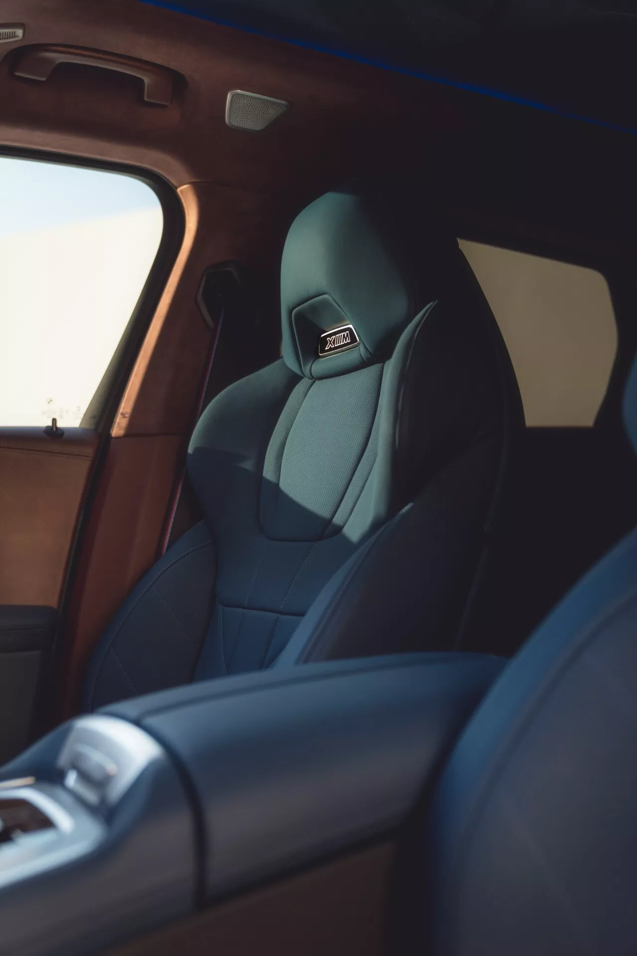 2023 BMW XM (G09) interior view focusing on the driver's seat and its high-end upholstery from a side perspective, highlighting technology features and luxury finishing.