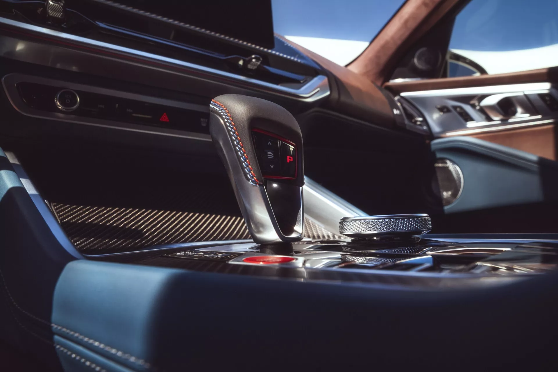2023 BMW XM (G09) interior featuring ergonomic gear shift lever with park indicator, sophisticated carbon-fiber trim around the modern iDrive controller, keyless start-stop button, luxury wood and leather finishes, and a glimpse into the automatic climate control system