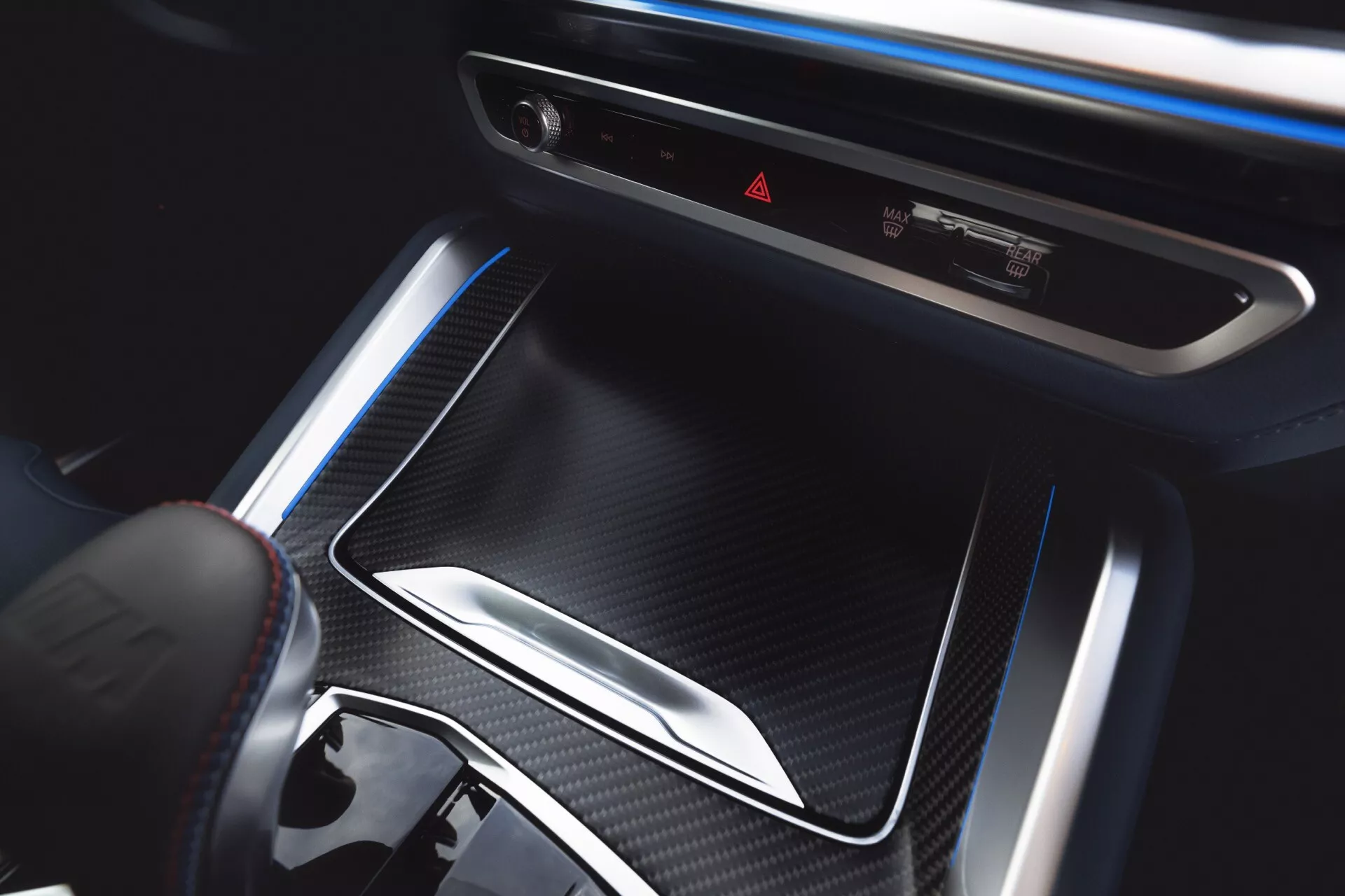Interior view of BMW XM 2023 (G09) focusing on center console with storage compartment, climate control system, ambient lighting, gear selector, and premium finishes