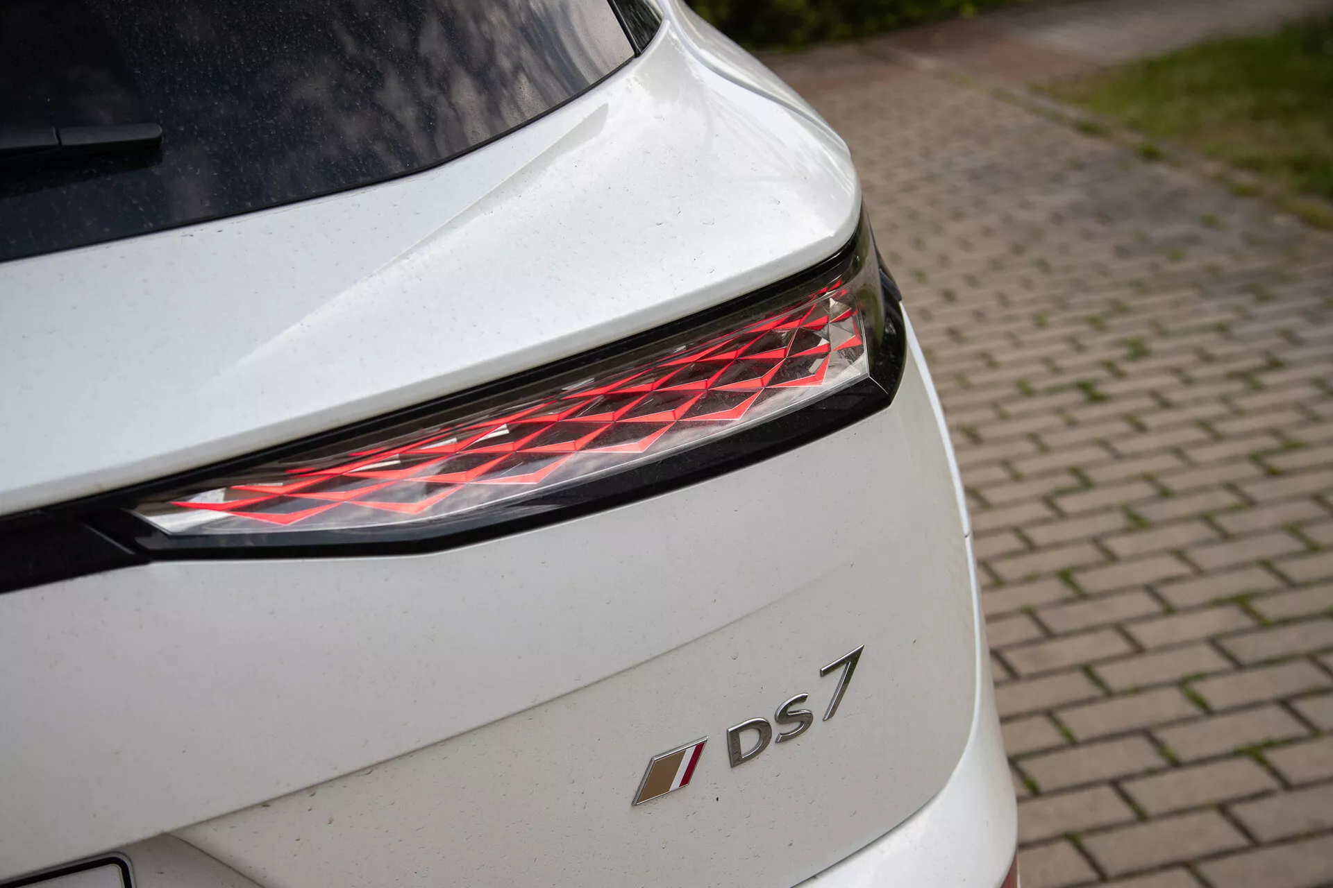 Close-up of white DS 7's rear section featuring modern LED taillight and model emblem, highlighting design details and premium finish