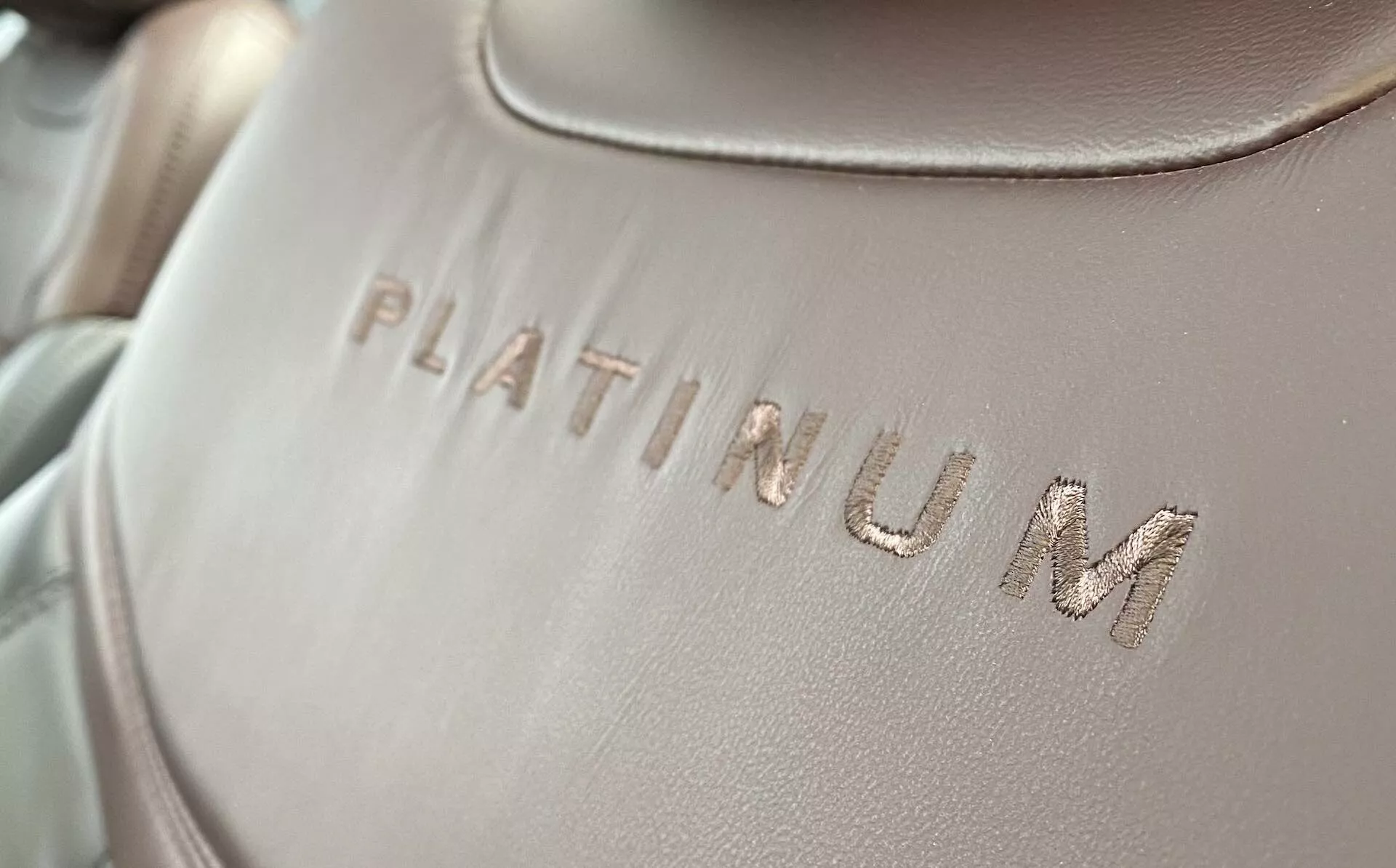 Close-up detail of the interior upholstery of a Ford Explorer 2019, featuring the word 'PLATINUM' embossed on a smooth fabric or leather surface, with a slight diagonal angle. The text is in focus, with soft, evenly distributed lighting and a shallow depth of field.