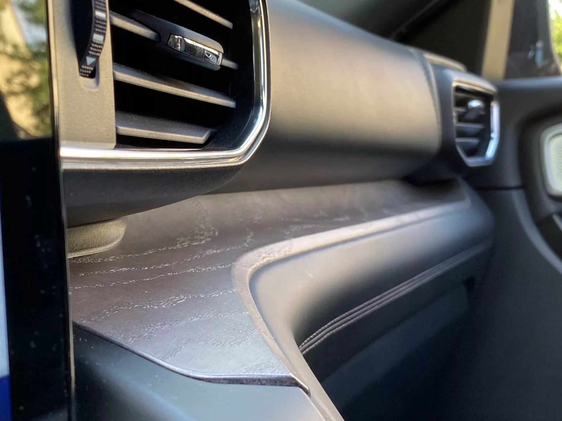 Close-up view of the 2019 Ford Explorer interior, focusing on the passenger's side dashboard area with adjustable air conditioning vent, metallic trim, textured dashboard surface, and a matching door panel, showcasing the vehicle's interior design and material quality.