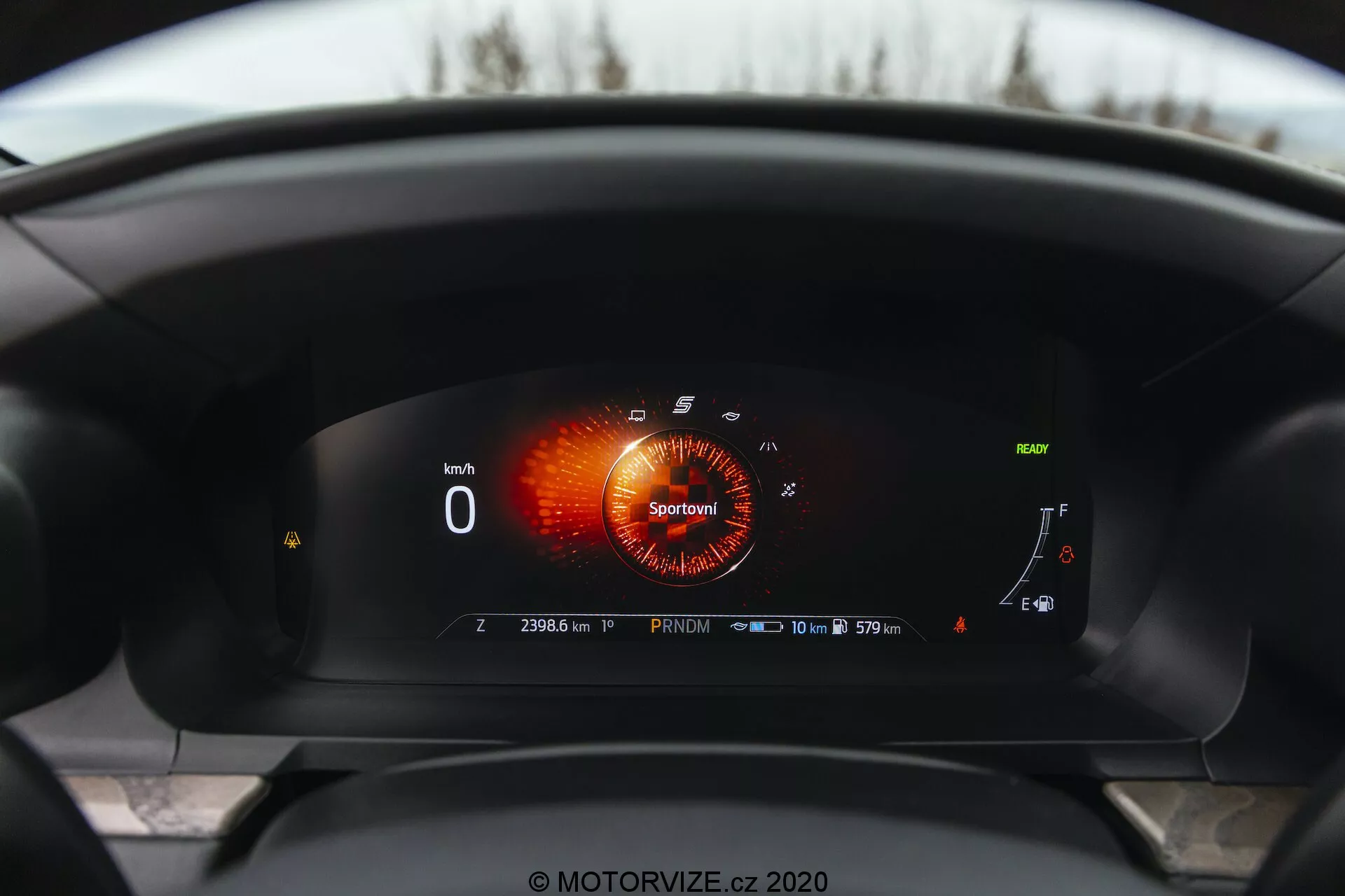 Interior view of a 2019 Ford Explorer from the driver's perspective, showcasing a fully digital instrument cluster. The digital screen displays a tachometer in 'Sport' mode with red-orange graphics, a speedometer showing '0 km/h,' a fuel gauge nearly full, a coolant temperature gauge on the lower end, and various indicators. Notably featured is an adaptive cruise control system symbol, a service interval reminder reading '10 000 km or 365 days,' and an odometer at '23063 km,' indicating the car is stationary in 'Park' mode. A nearly full battery icon suggests hybrid or electric capabilities.