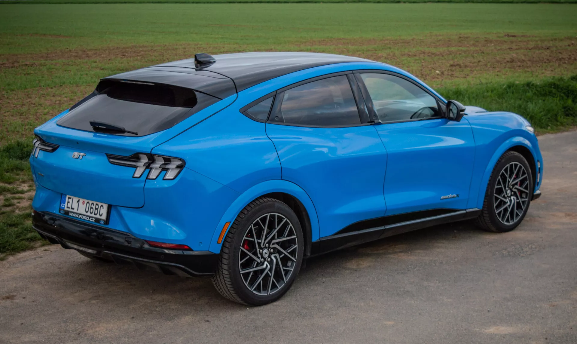 2020 Ford Mustang Mach-E bright blue electric SUV in a dynamic three-quarter rear view highlighting aerodynamic design, sleek tail lights, and sporty alloy wheels, showcasing advanced technology and electric propulsion.