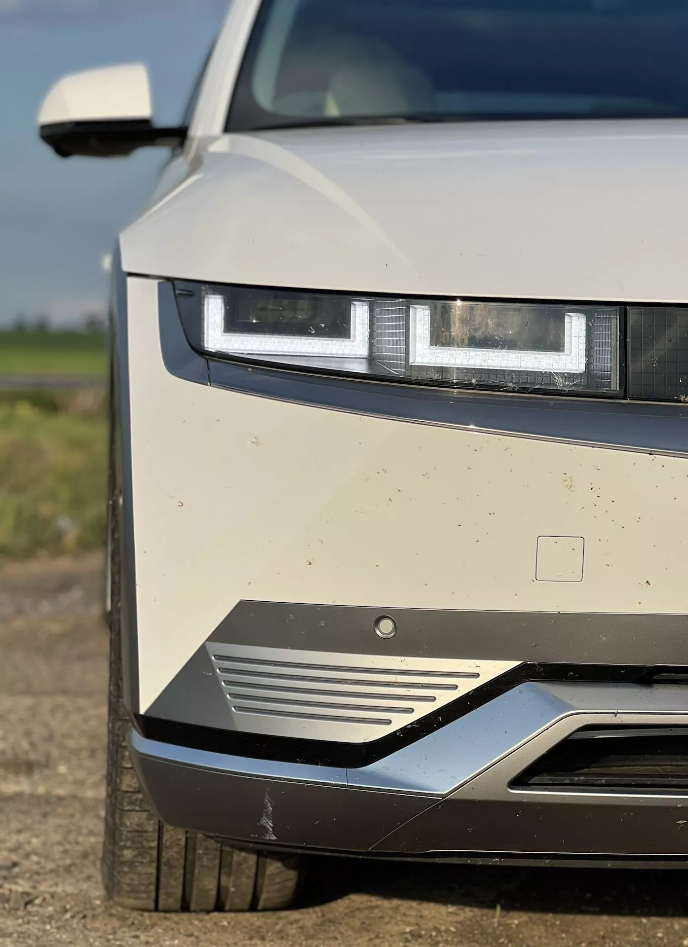 2021 Hyundai Ioniq 5 close-up view highlighting LED headlights, front grille design, and aerodynamic features, with visible dirt indicating recent use