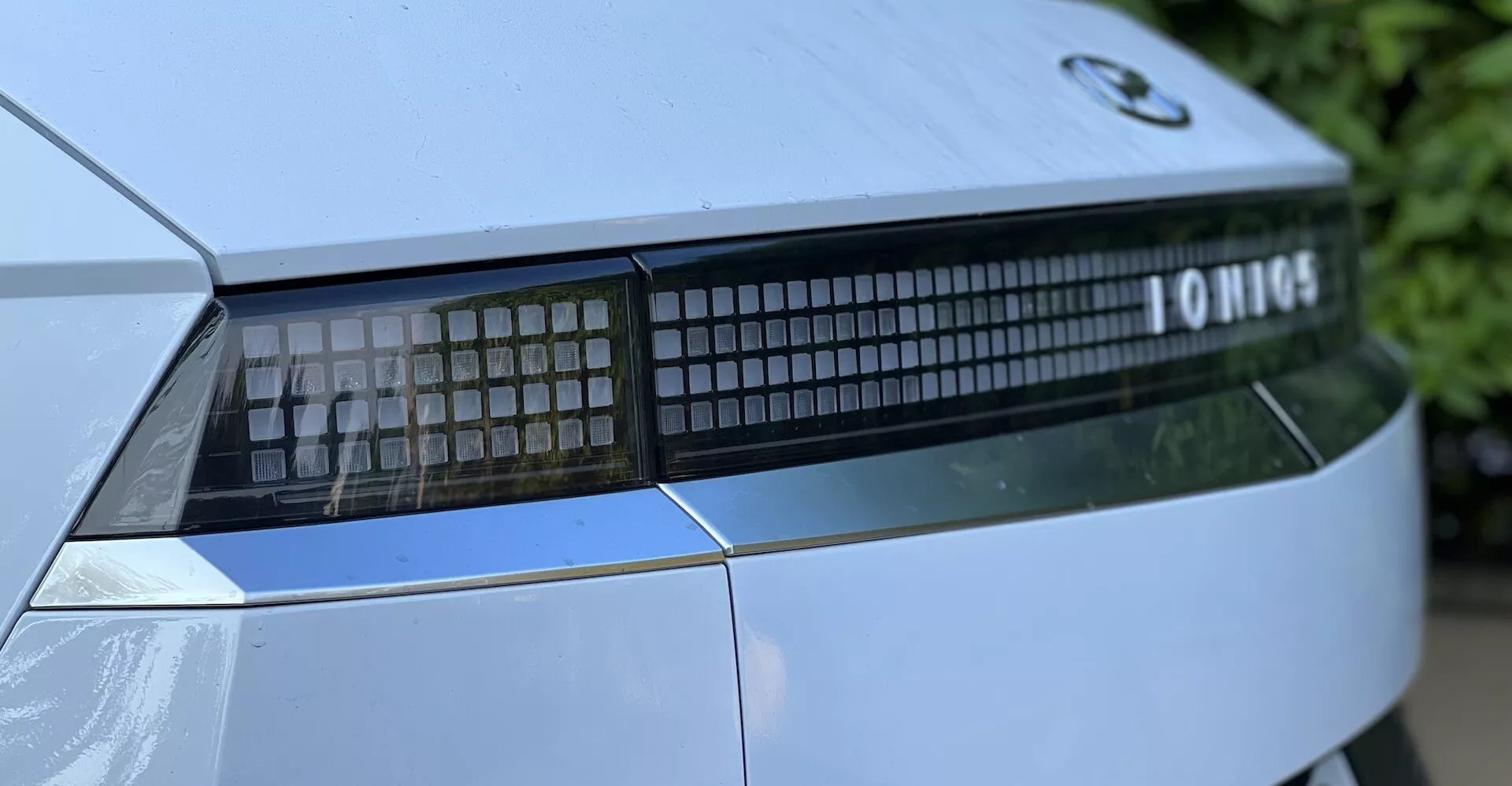Close-up of a 2021 Hyundai Ioniq-5 showcasing the rear light assembly and trunk detail from a low angle, highlighting the linear LED light signature and modern design.