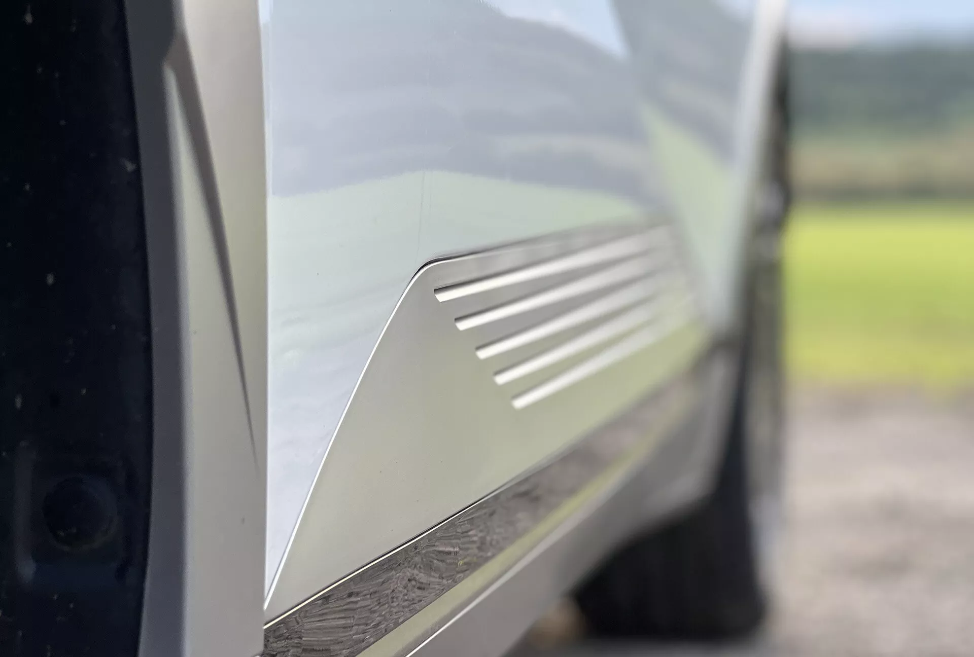 Close-up view of a Hyundai Ioniq-5 2021 focusing on the detailed design of the air vent on the rear quarter panel, painted in a glossy light color, emphasizing the vehicle's aerodynamic features and aesthetic beauty.