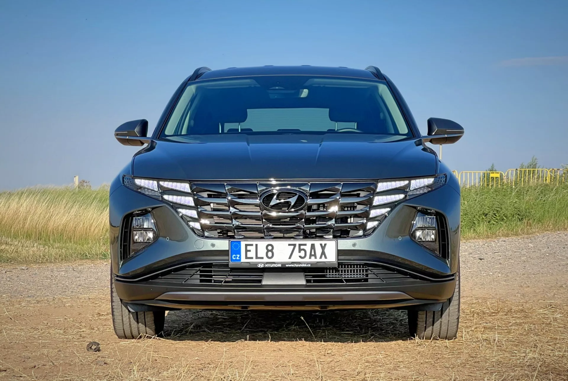 2020 Hyundai Tucson front view showcasing aerodynamic hood design, cascading grille, sharp LED headlamps, and detailed bumper with possible technology features, situated on a natural landscape background