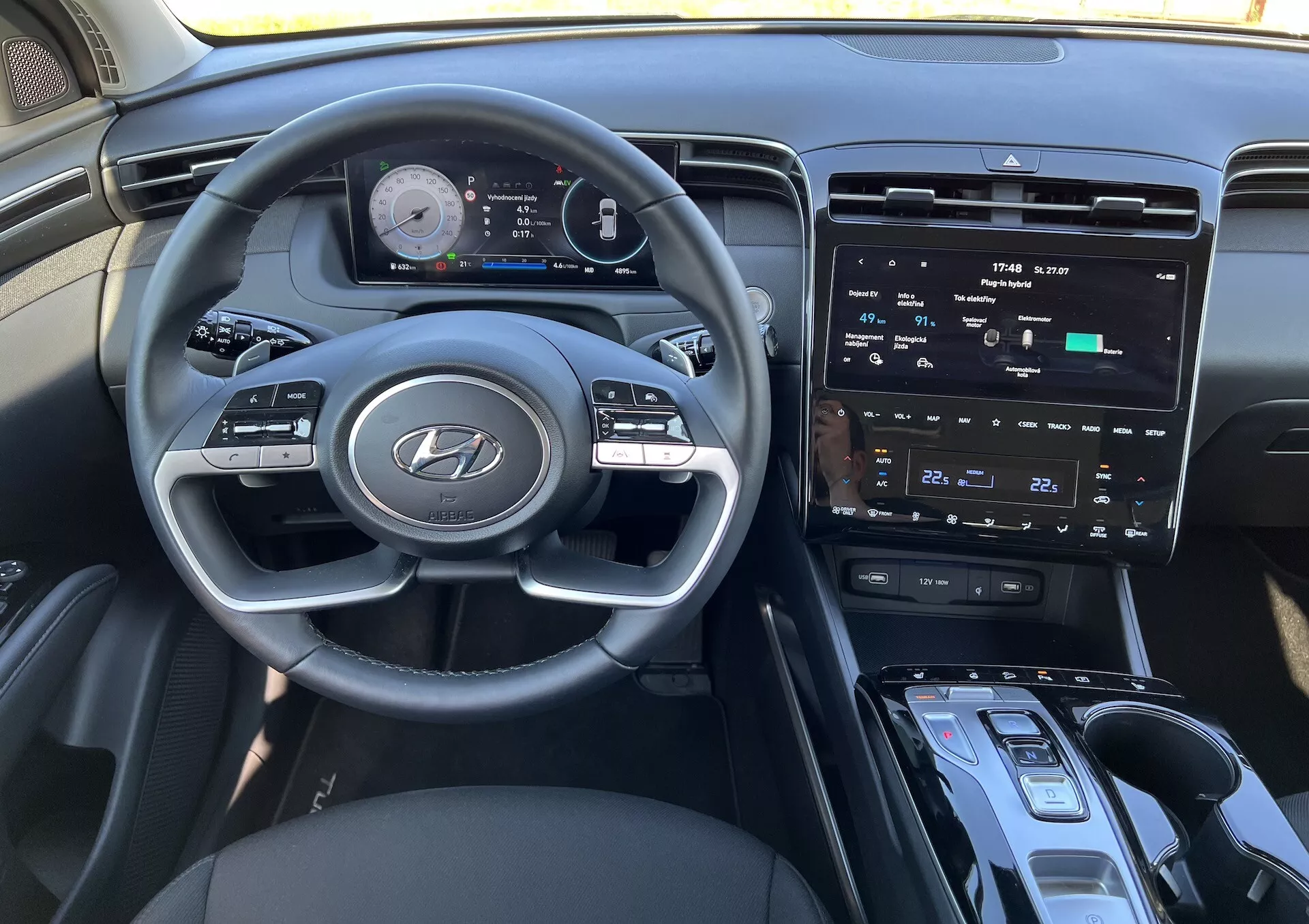2020 Hyundai Tucson interior showcasing the steering wheel with Hyundai logo, advanced digital instrument cluster, center infotainment touchscreen, climate controls, start/stop ignition button, gear shift lever, and possible wireless charging area from the driver's perspective