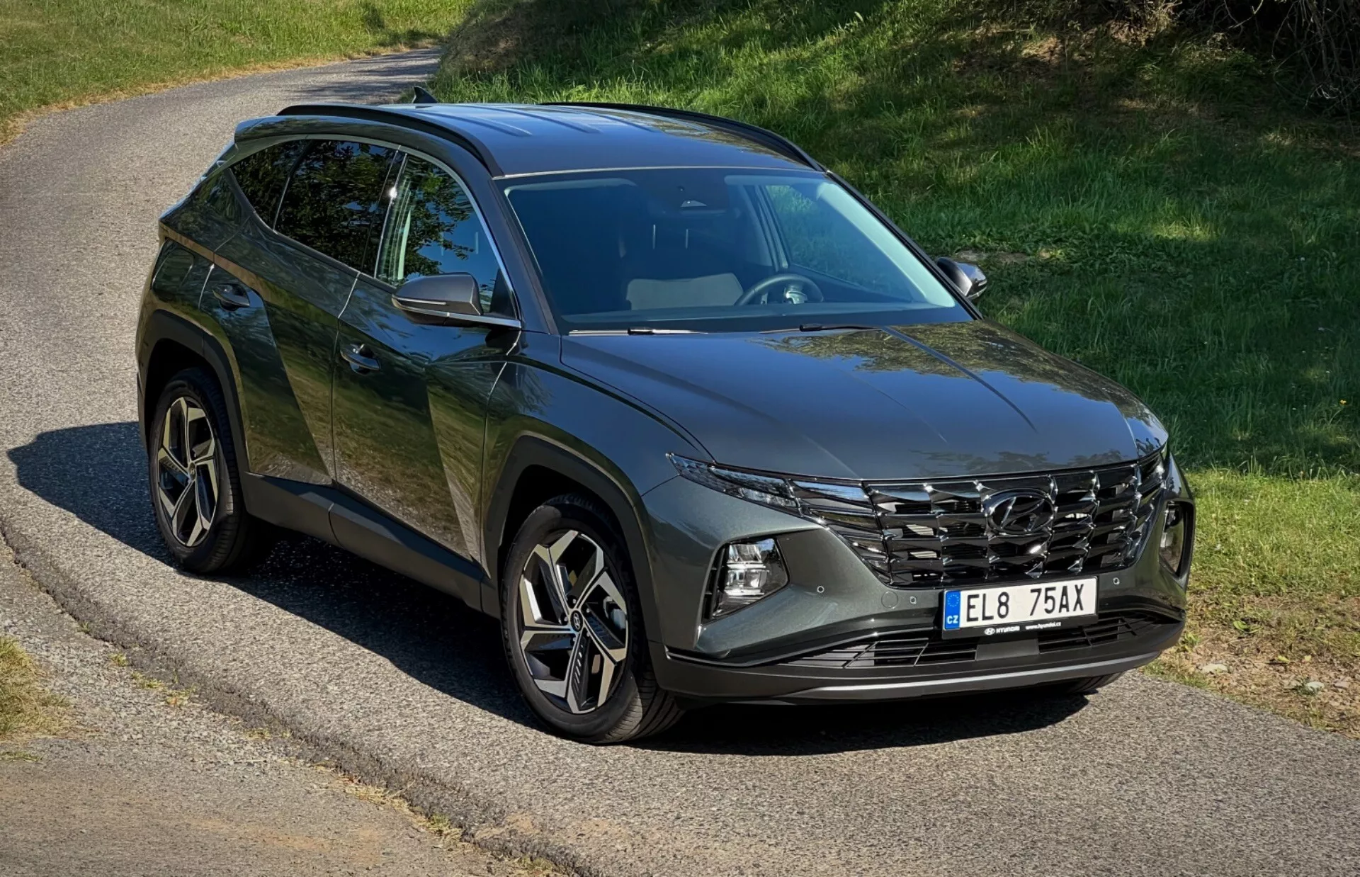 2020 Hyundai Tucson SUV parked on a secluded road showcasing its front grille, LED headlights, alloy wheels and body lines under natural sunlight