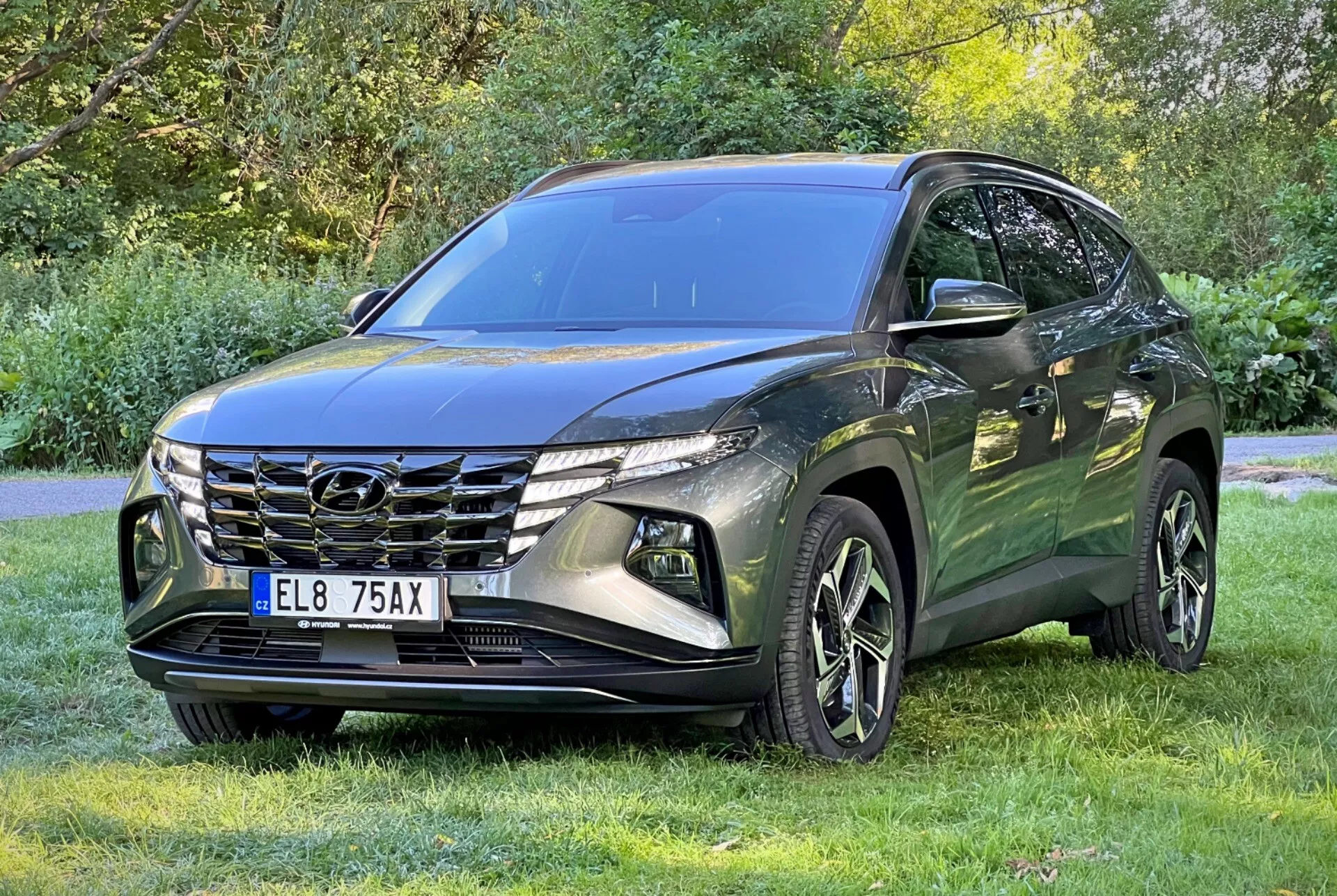 2020 Hyundai Tucson SUV parked on grass with trees in background showcasing the front grille, LED headlights, and alloy wheels