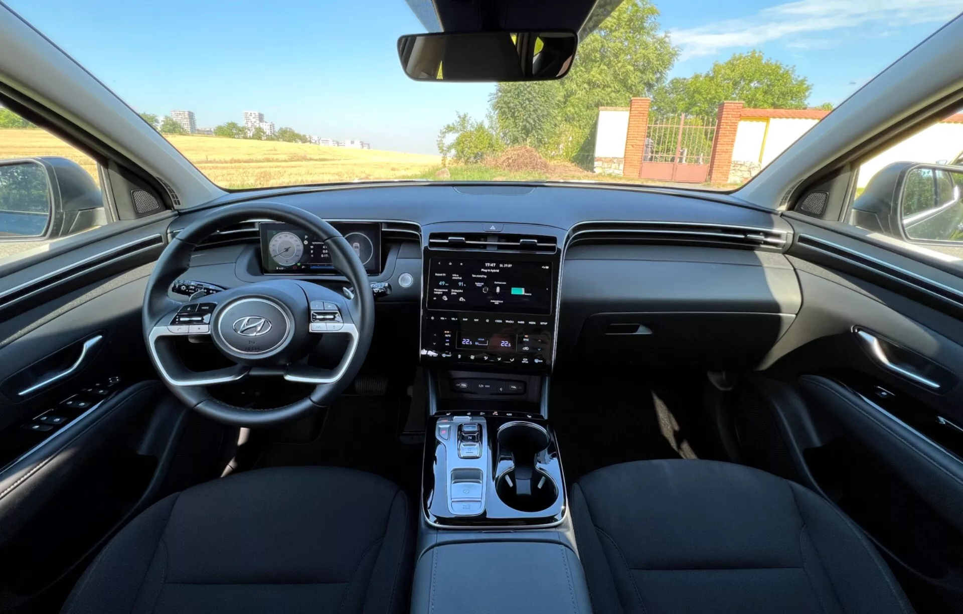 2020 Hyundai Tucson interior showcasing front seats, steering wheel with manufacturer's logo and control buttons, digital instrument cluster, vertical touchscreen infotainment system on center console, automatic gear shifter, and dual-tone dashboard design in eye-level view resembling driver's perspective