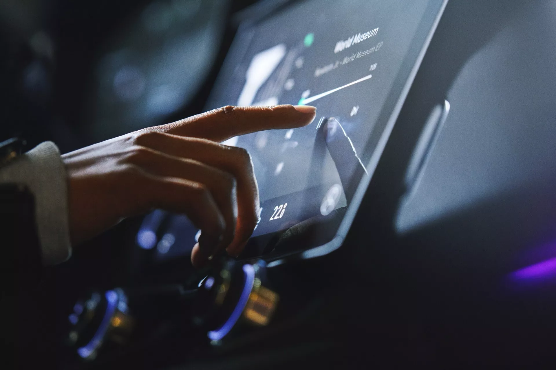 Close-up view of a person's hand interacting with the Lynk & Co 01 (2021 - 1st generation) infotainment touchscreen, emphasizing modern automotive technology and ergonomic design