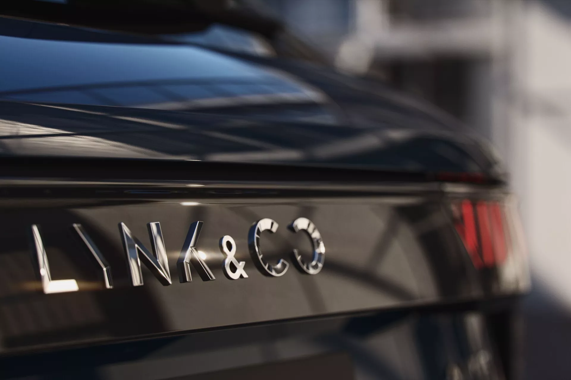 Close-up of the LYNK & CO logo on the rear of a 2021 1st generation vehicle, showcasing a luxurious glossy black finish and a modern, metallic typeface against a softly blurred background.