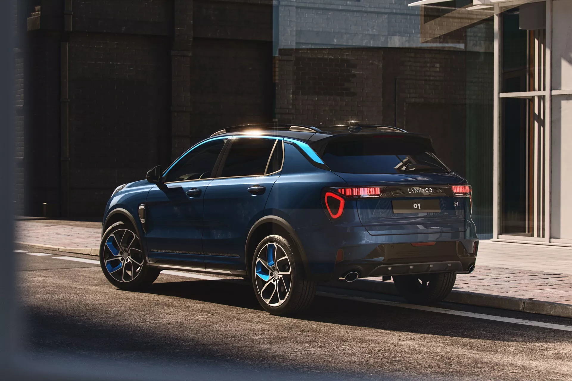 2021 Lynk & Co 01 SUV in modern urban environment, showcased in natural sunlight with a three-quarter rear view highlighting sleek design, rear LED taillights, dual exhaust, large alloy wheels, and practical roof rails
