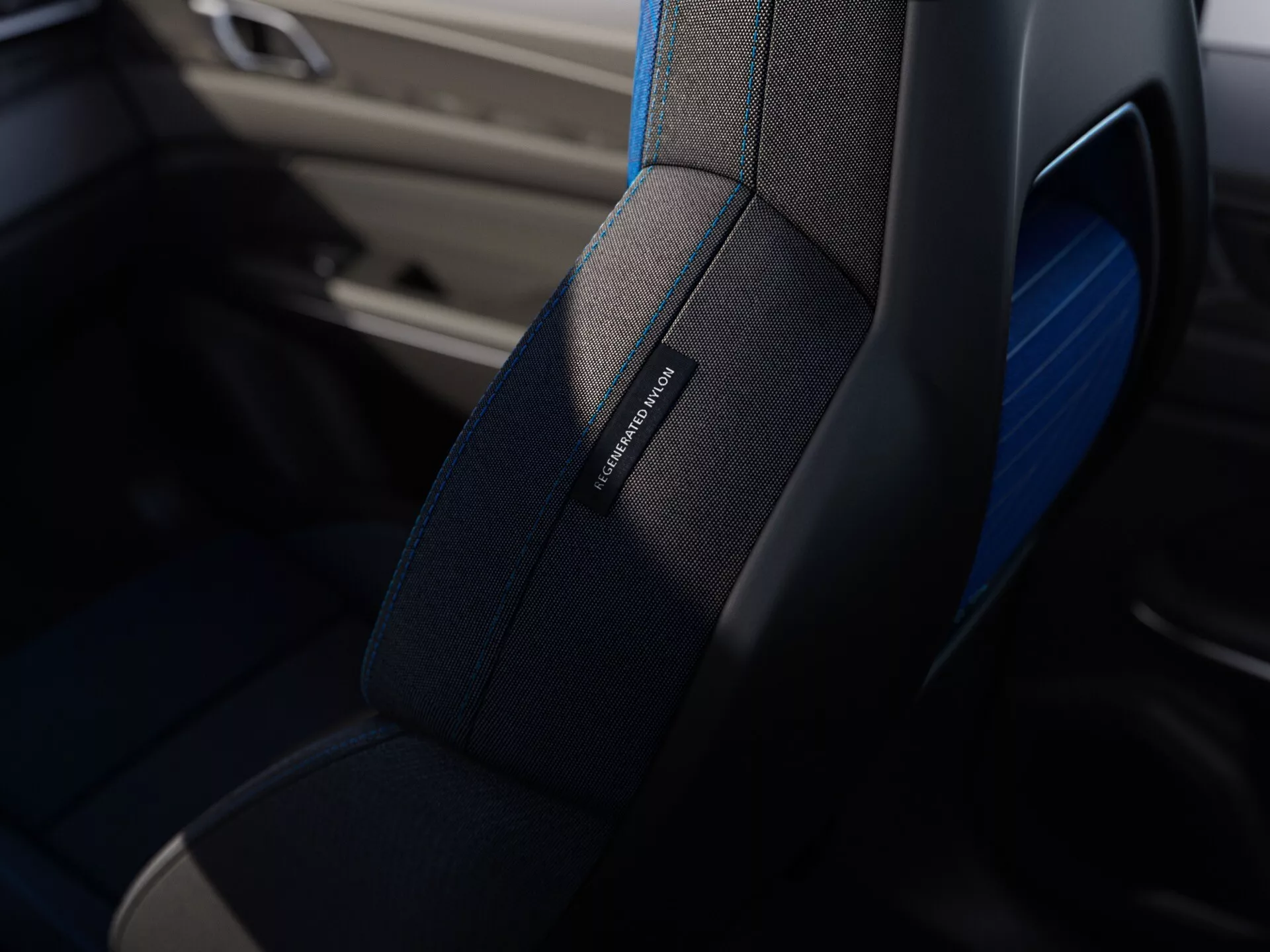 Close-up view of a high-quality car seat with fine stitching, subtle blue trim, and a model name badge, suggesting luxury or sportiness, from the Lynk & Co 01 2021