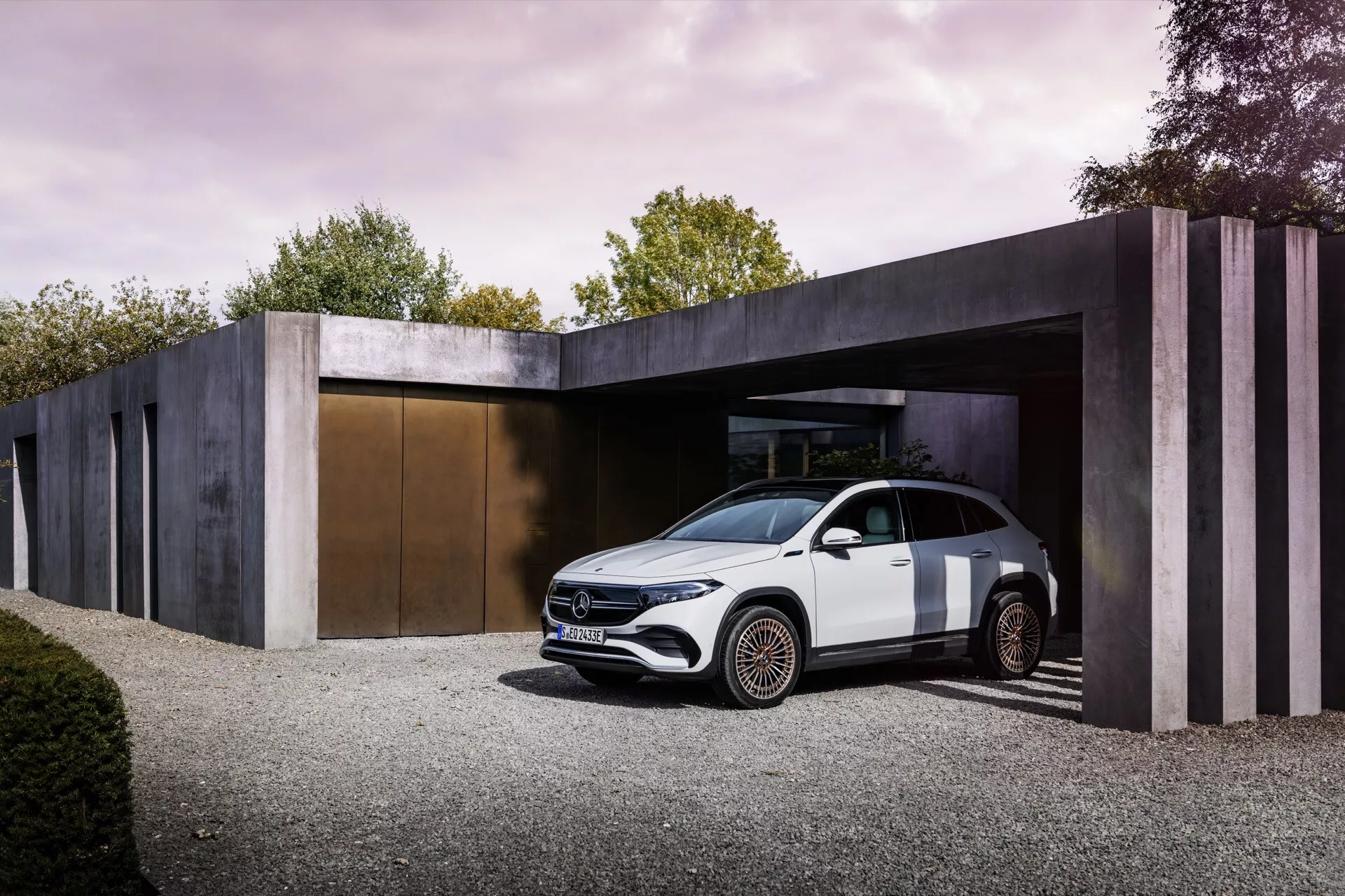 2021 Mercedes-Benz EQA parked at a minimalist-style building entrance showcasing its front three-quarter view under soft daylight, highlighting its sleek aerodynamic design, LED headlights, high shoulder line, coupe-like silhouette, flush door handles, intricately designed alloy wheels, and potential for advanced driving assistance systems.