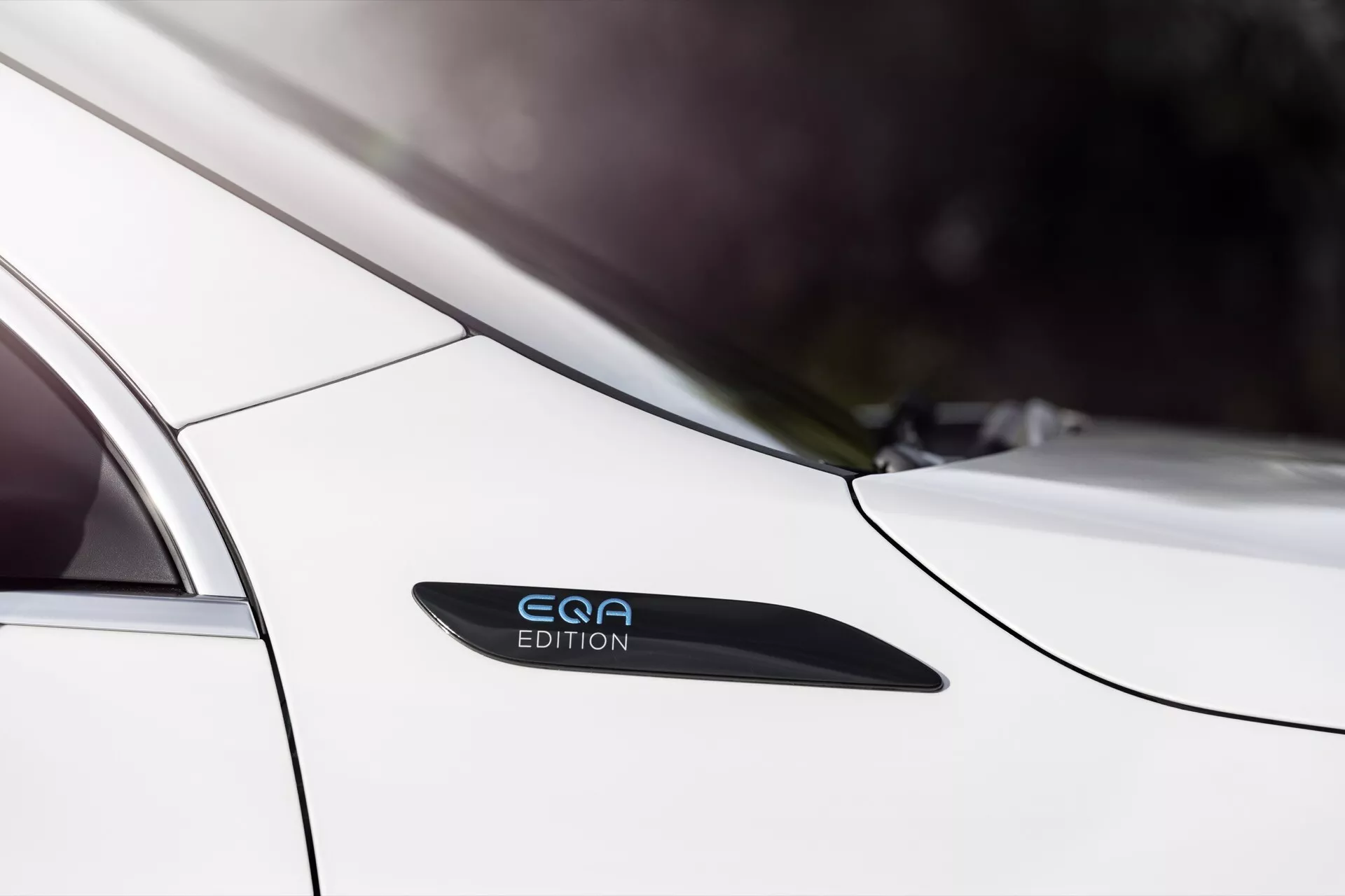 Close-up of Mercedes-Benz EQA 2021 showing the sleek side profile near the rear passenger door and back fender, highlighting the white paint, 'EQE EDITION' badge, handle-less door design, and design lines suggesting modern aesthetics and advanced technology.