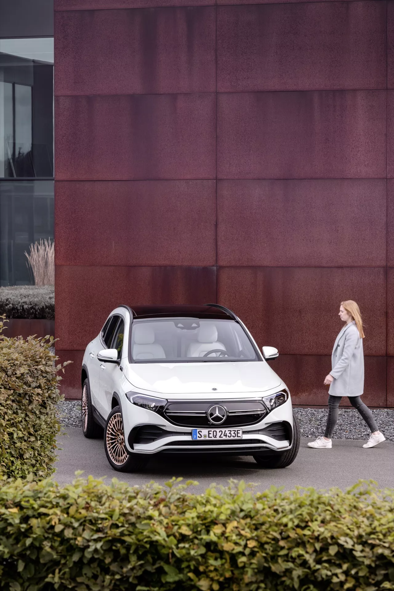 2021 Mercedes-Benz EQA 250 parked in urban setting with distinct red panel building facade, showcasing electric compact SUV design and advanced features like LED headlights and aerodynamic wheels