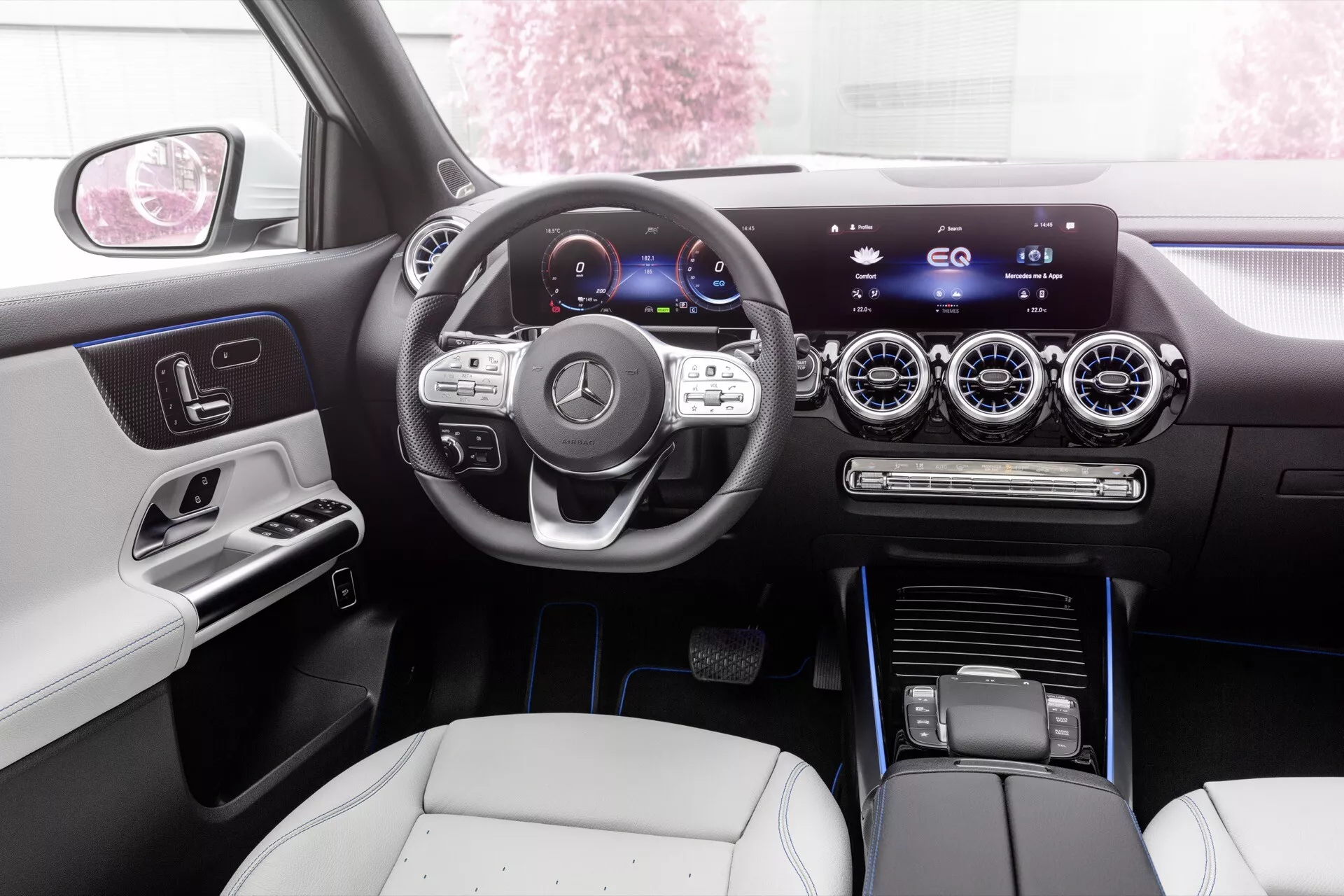 Interior view of Mercedes-Benz EQA 2021 showing the sleek dashboard, digital instrument cluster, multifunction steering wheel, and central touchscreen infotainment system from the backseat perspective