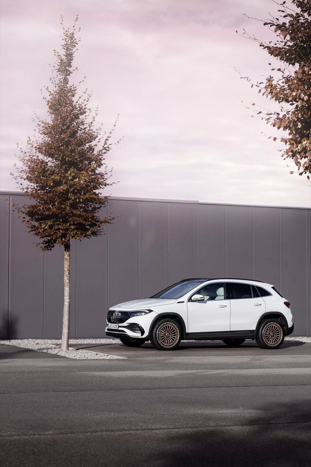 2021 Mercedes-Benz EQA side profile parked on urban street, showcasing its modern SUV design with flowing lines, pronounced wheel arches, contrasting black trim, and multi-spoke alloy wheels against an overcast backdrop