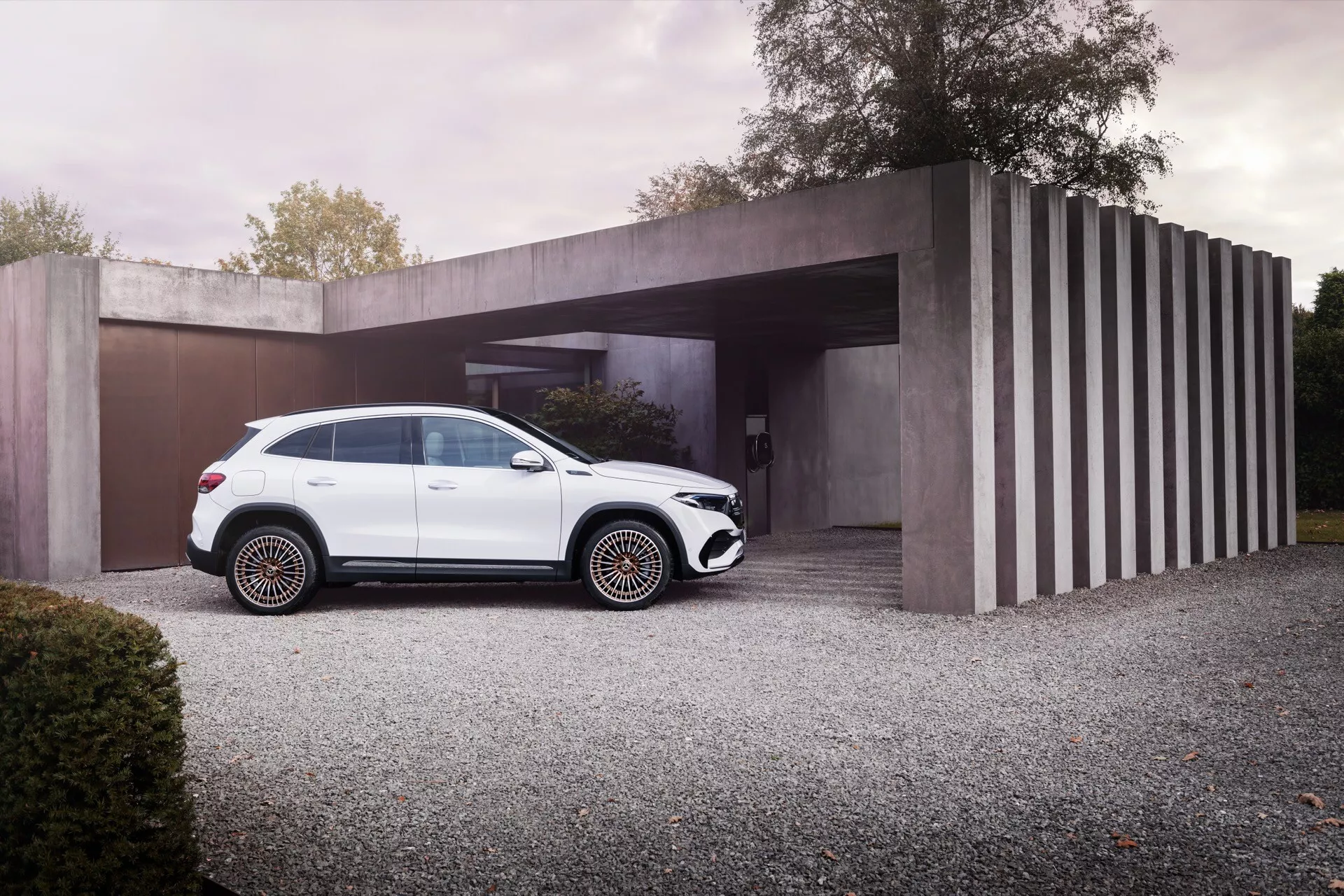 2021 Mercedes-Benz EQA luxury SUV in white parked on a gravel driveway with modern minimalist house in the background, showcasing sleek design, black trim features, multi-spoke rims, and roof rails