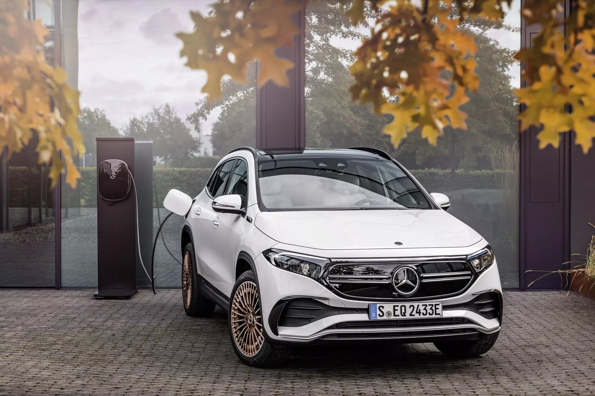 2021 Mercedes-Benz EQA 243 white luxury SUV featuring a three-quarter view showcasing its modern LED headlights, distinctive alloy wheels, and electric vehicle charging technology, surrounded by a hint of autumn leaves, highlighting its eco-friendly design in a luxurious outdoor setting