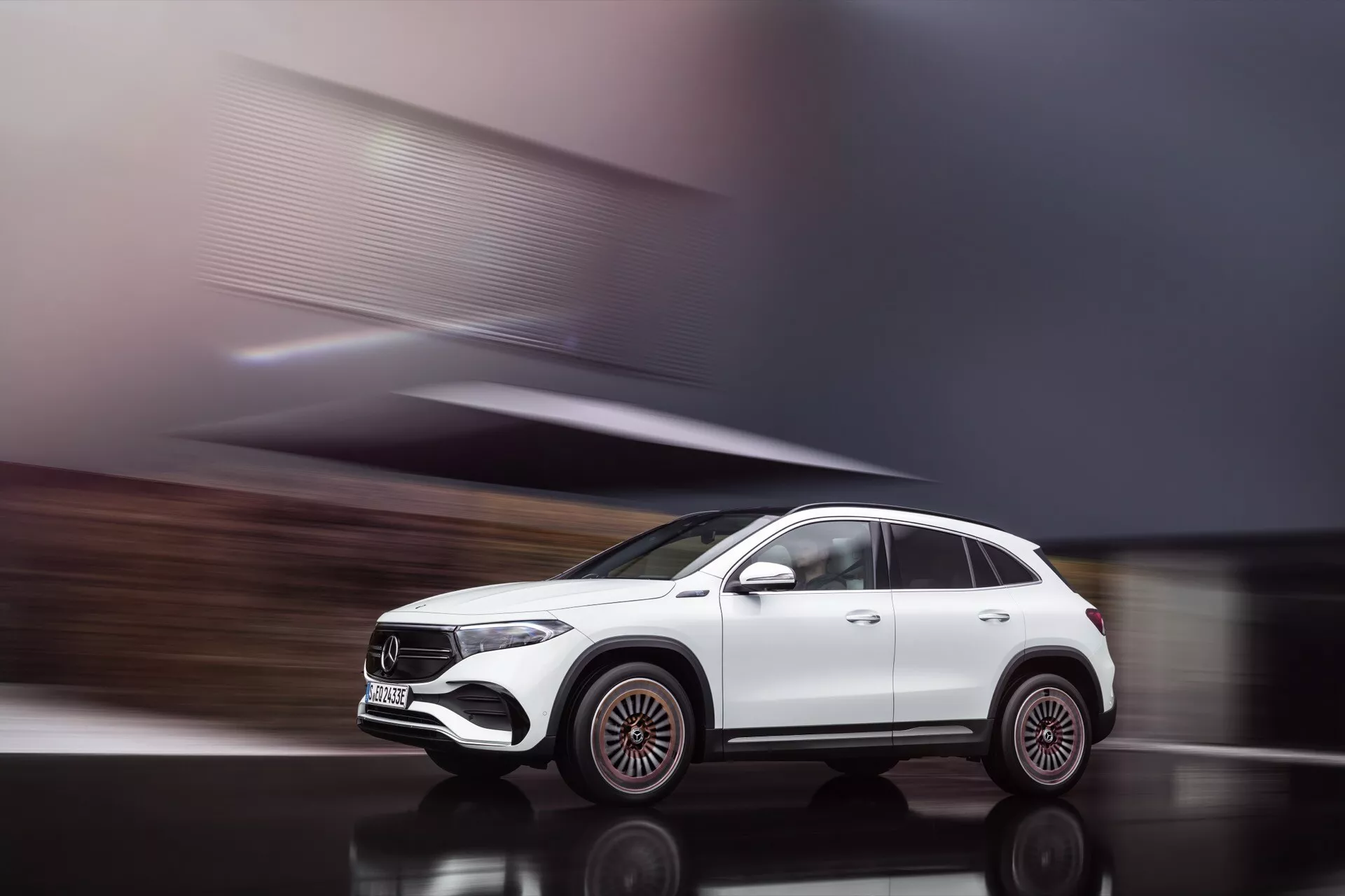 Dynamic side profile shot of a white Mercedes-Benz EQA 2021 SUV in motion, showcasing distinctive large alloy wheels, sleek headlight design, and modern aerodynamic exterior