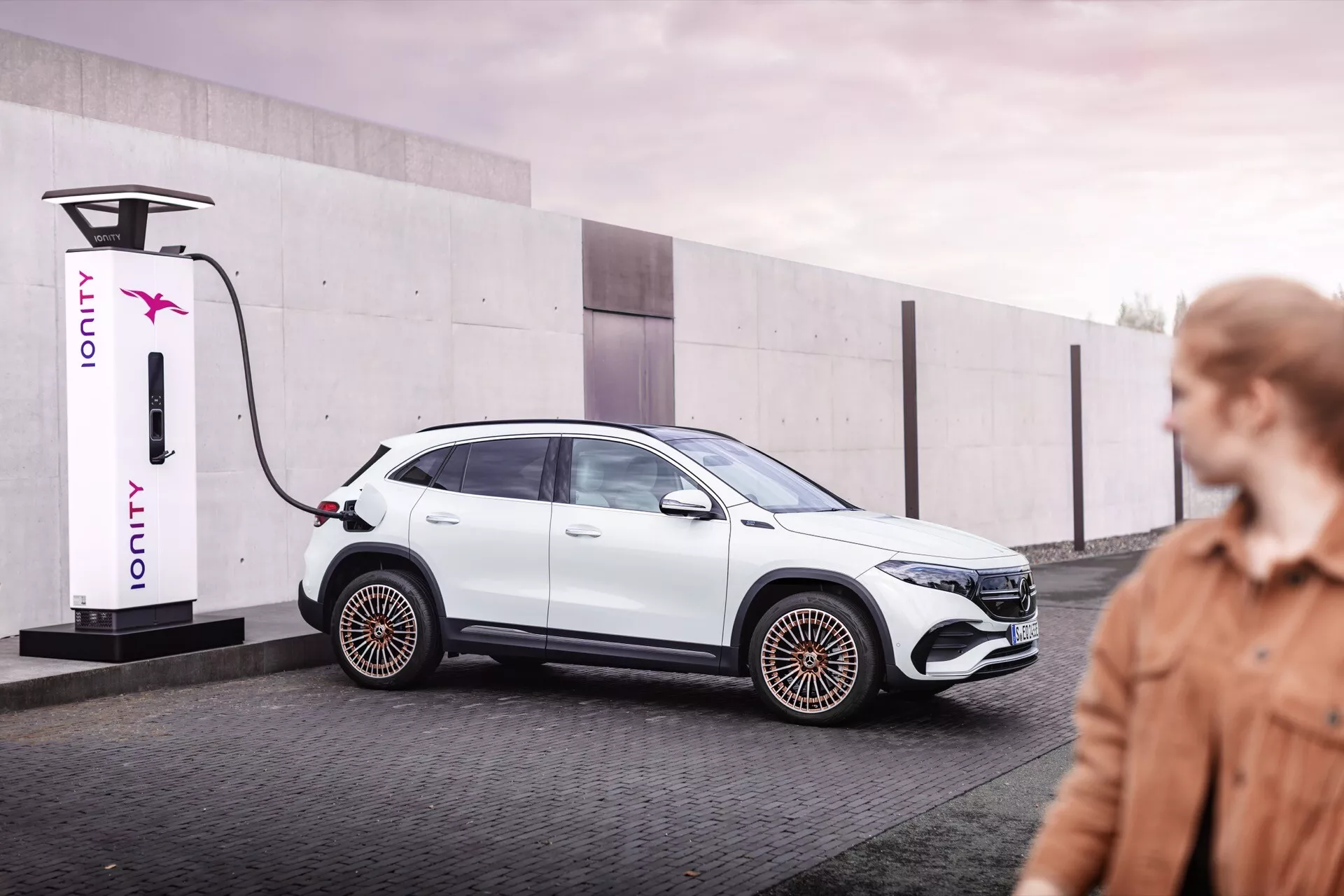 2021 Mercedes-Benz EQA electric car connected to IONITY charging station, showcasing sleek design and aerodynamic features in a urban environment