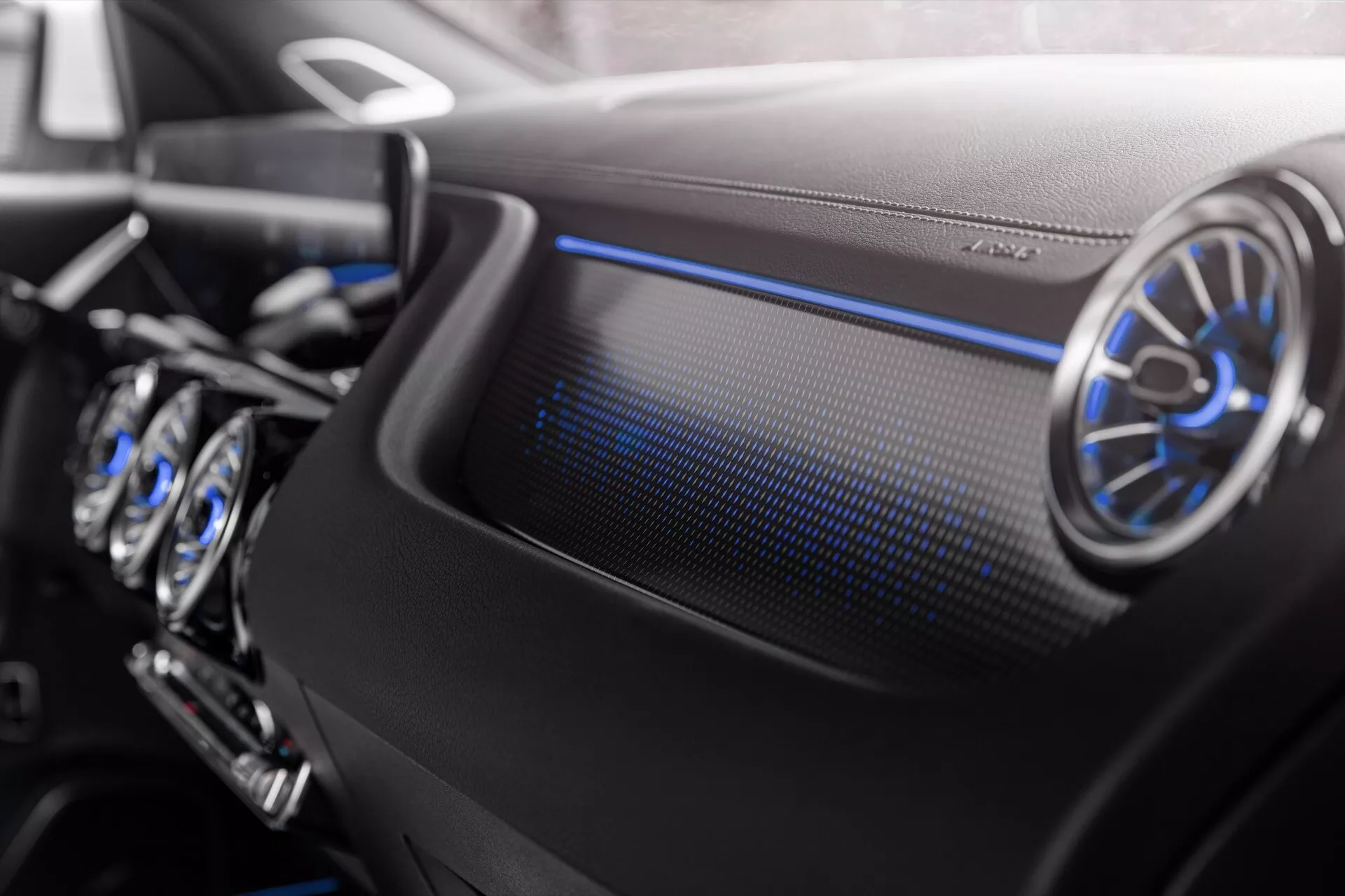 Close-up of the Mercedes-Benz EQA 2021 interior showing the passenger side dashboard with circular metallic air vent and cool blue ambient lighting, highlighting luxury design and advanced technology features