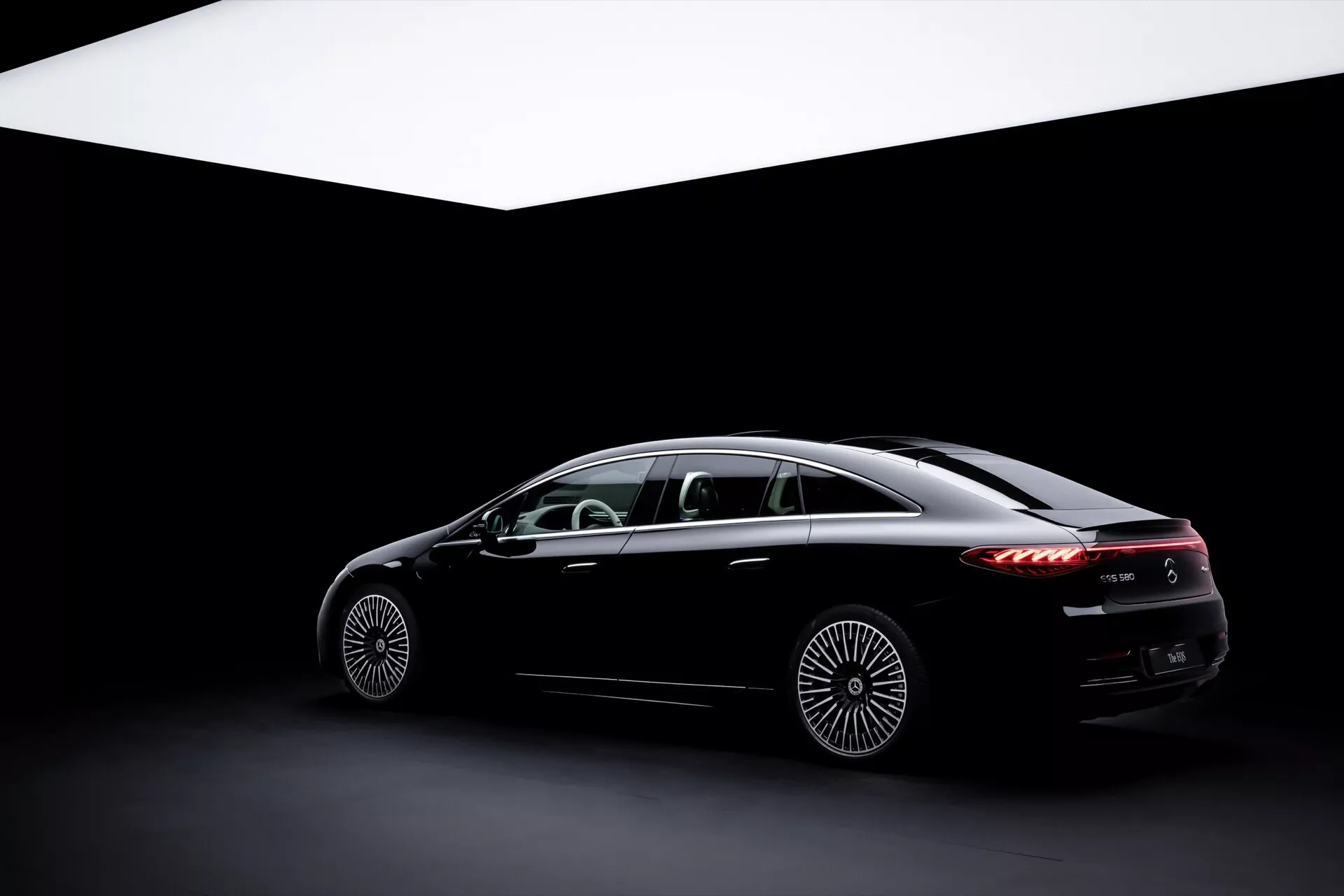 2024 Mercedes-Benz EQS luxury sedan showcasing advanced design and technology features, captured from low side angle highlighting aerodynamic profile and elegant details in a studio setting