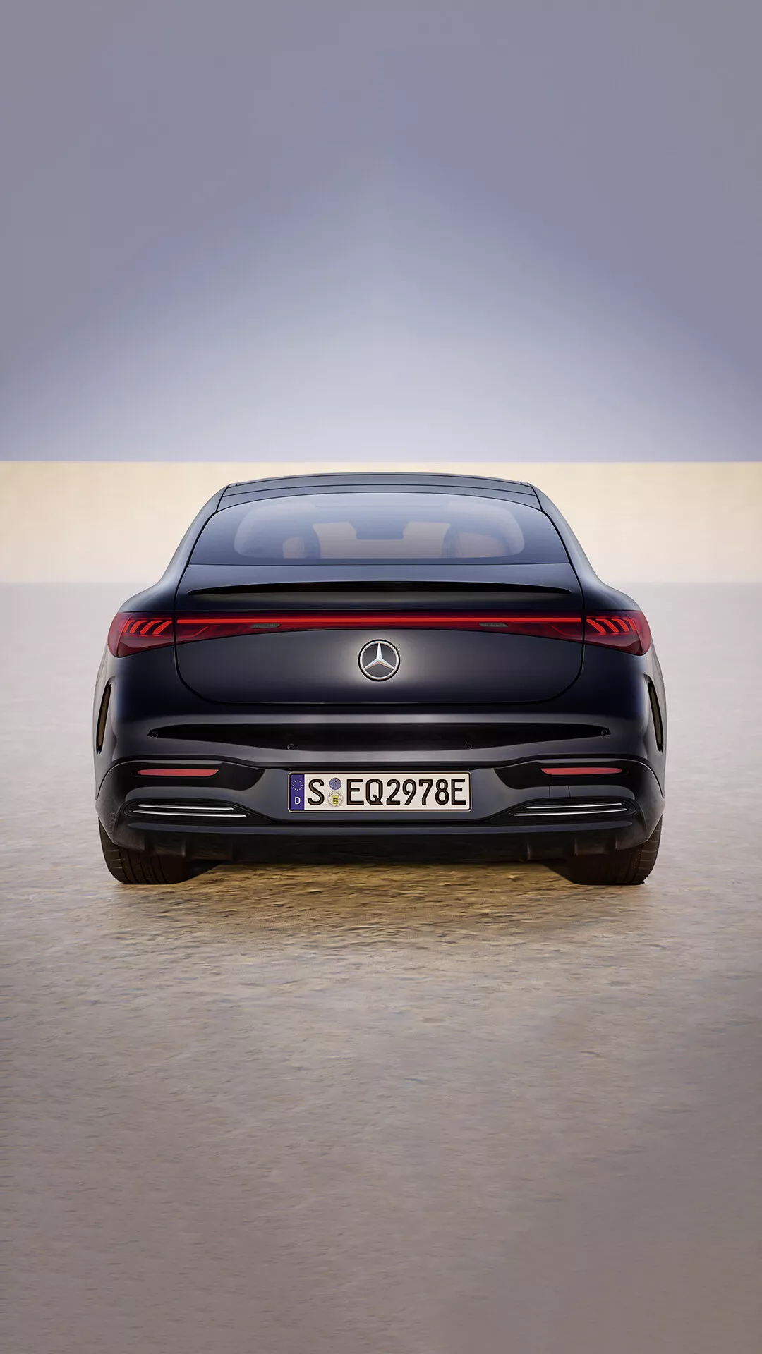 2024 Mercedes-Benz EQS facelift rear view showcasing LED tail light strip, flush-mounted parking sensors, and electric vehicle designation on a reflective showroom floor