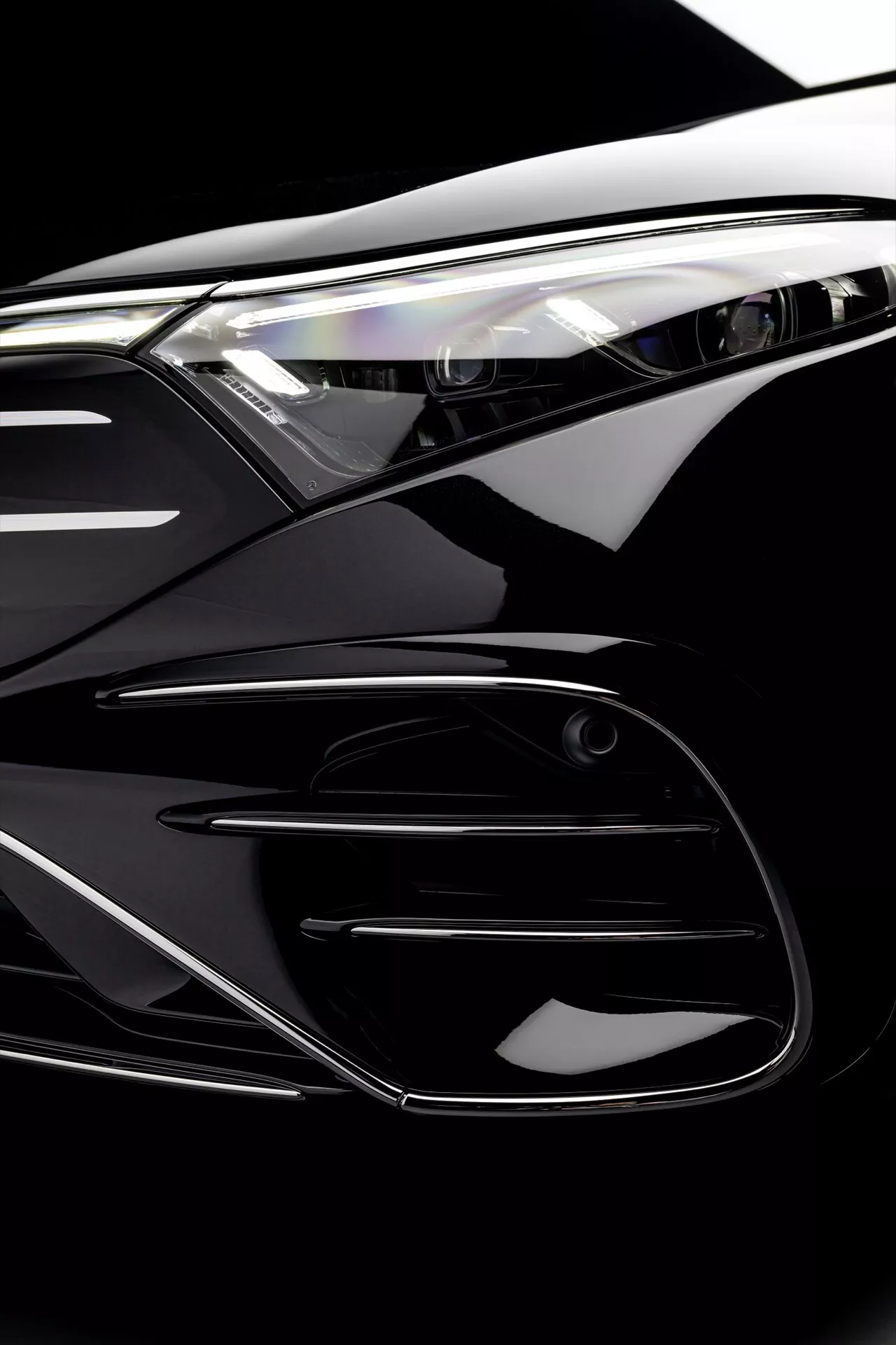 Close-up view of the 2024 Mercedes-Benz EQS facelift showing detailed features of the headlight, grille, and bumper, highlighting the car's aerodynamic design and advanced lighting technology