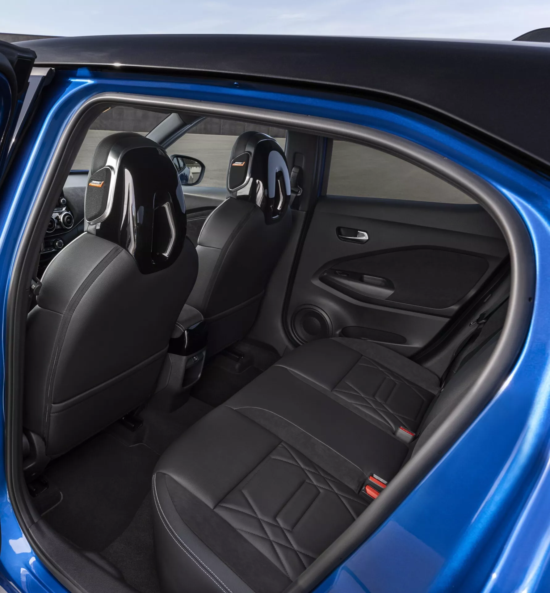 2019 Nissan Juke (F16) interior view from the rear passenger perspective showcasing black leather seats, driver-side door controls, and integrated audio system