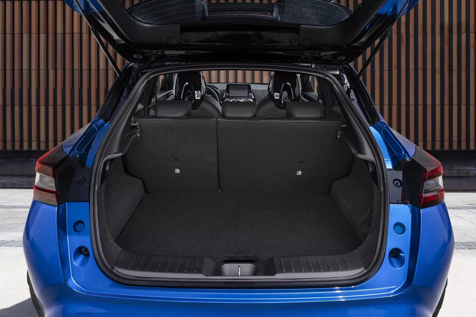 Rear view of a blue 2019 Nissan Juke F16 with open trunk showcasing cargo space and design features in daylight