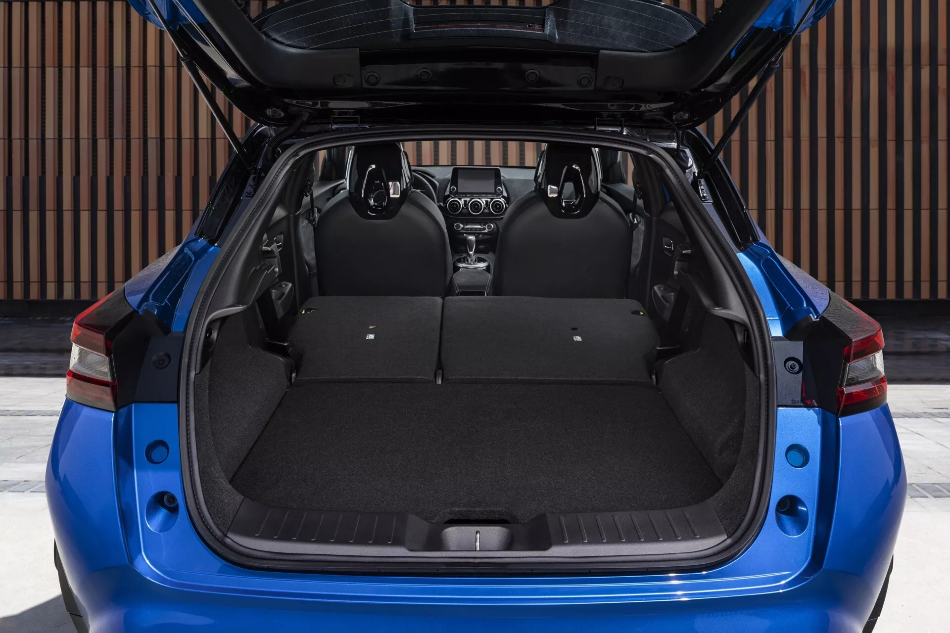 2019 Nissan Juke F16 in blue, rear view with open hatch showcasing spacious cargo area, split-folding rear seats, and visible retractable cargo cover