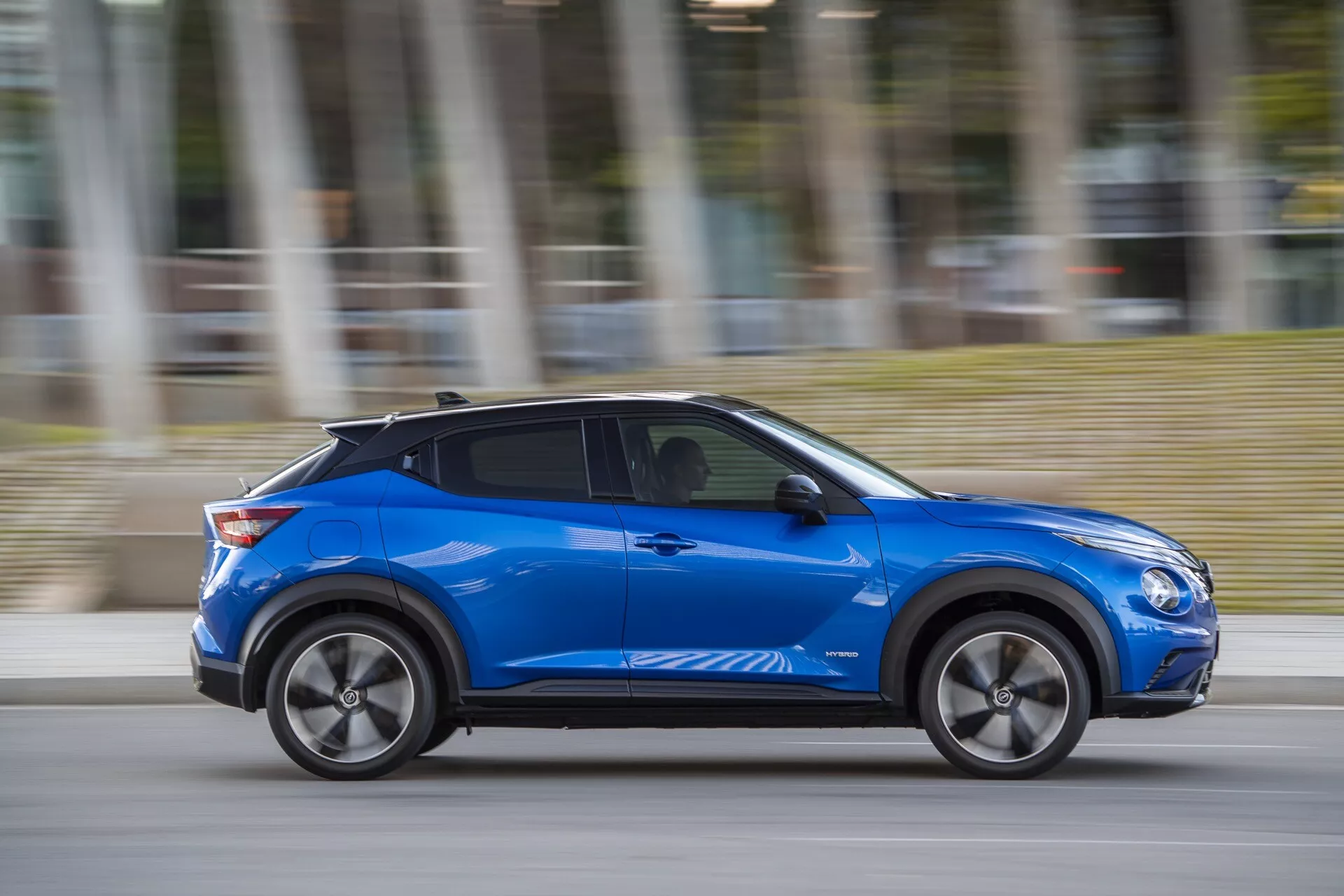 2019 Nissan Juke (F16) in blue, showcasing modern design and technology-driven features such as aerodynamic body lines, alloy wheels, and potential keyless entry, moving dynamically with motion blur on an overcast day