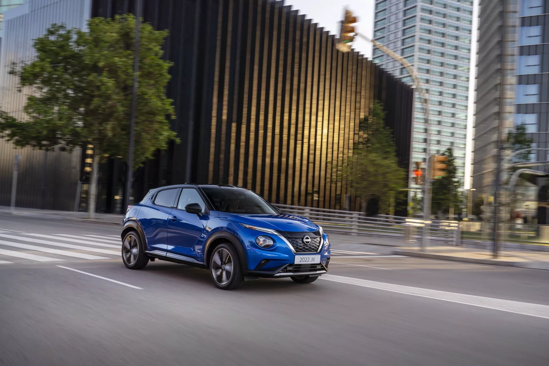 2019 Nissan Juke (F16) modern compact SUV in motion, captured from a side perspective in bright blue, showcasing the vehicle's design, dynamic presence, and aerodynamic features against an urban backdrop.
