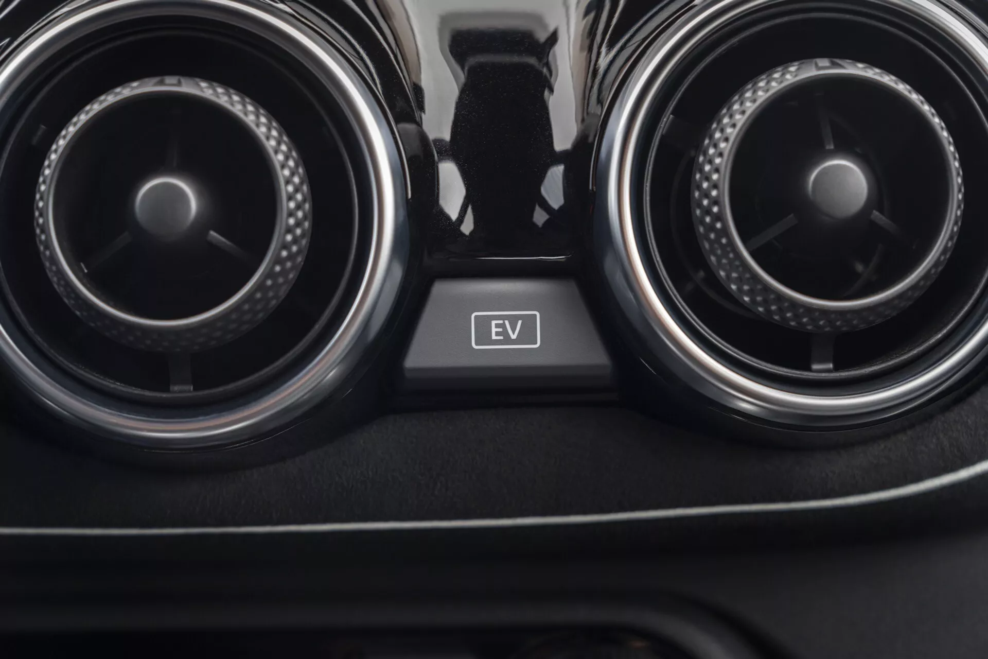 Close-up view of Nissan Juke 2019 (F16) interior focusing on air conditioning vents and EV mode button between them, showcasing car climate control and electric vehicle technology.