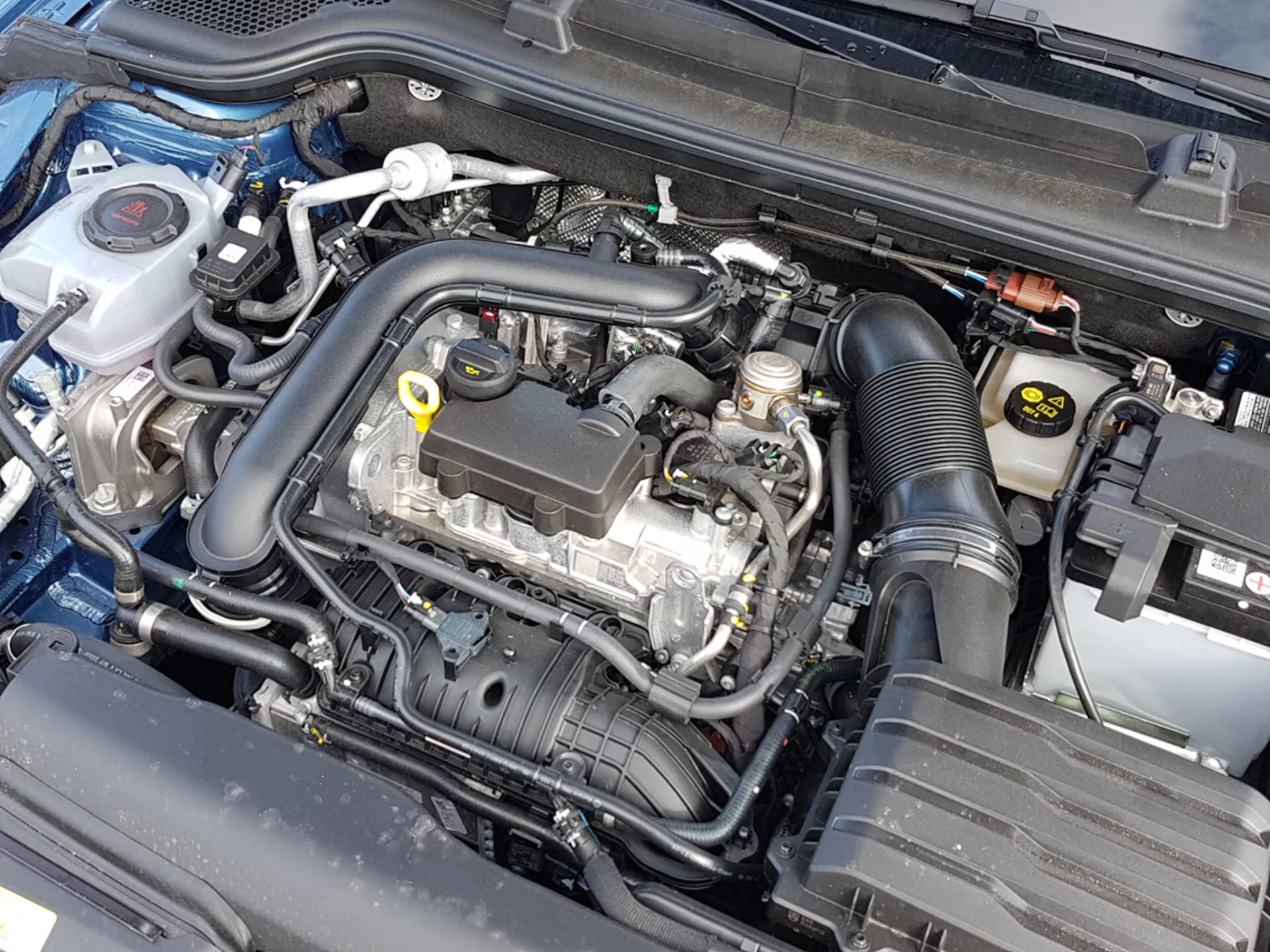 Close-up view of a Skoda Scala 2019 engine bay with open hood, showcasing the engine block and various components like coolant container, air filter housing, and battery, indicative of automotive engineering and maintenance attention.