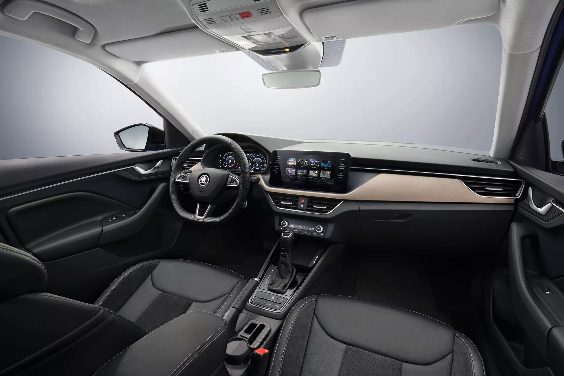 2019 Skoda Scala interior view showcasing driver and passenger areas, featuring left-hand drive steering wheel with integrated controls, modern dashboard with brushed metal accents, digital instrument cluster behind the steering wheel, 8-inch touchscreen infotainment system, minimalistic center console with automatic shift-by-wire gear selector, black leather-accented seats, and advanced vehicle technology including automatic climate control and connectivity features, under soft studio lighting emphasizing the car's spacious layout and ergonomic design.